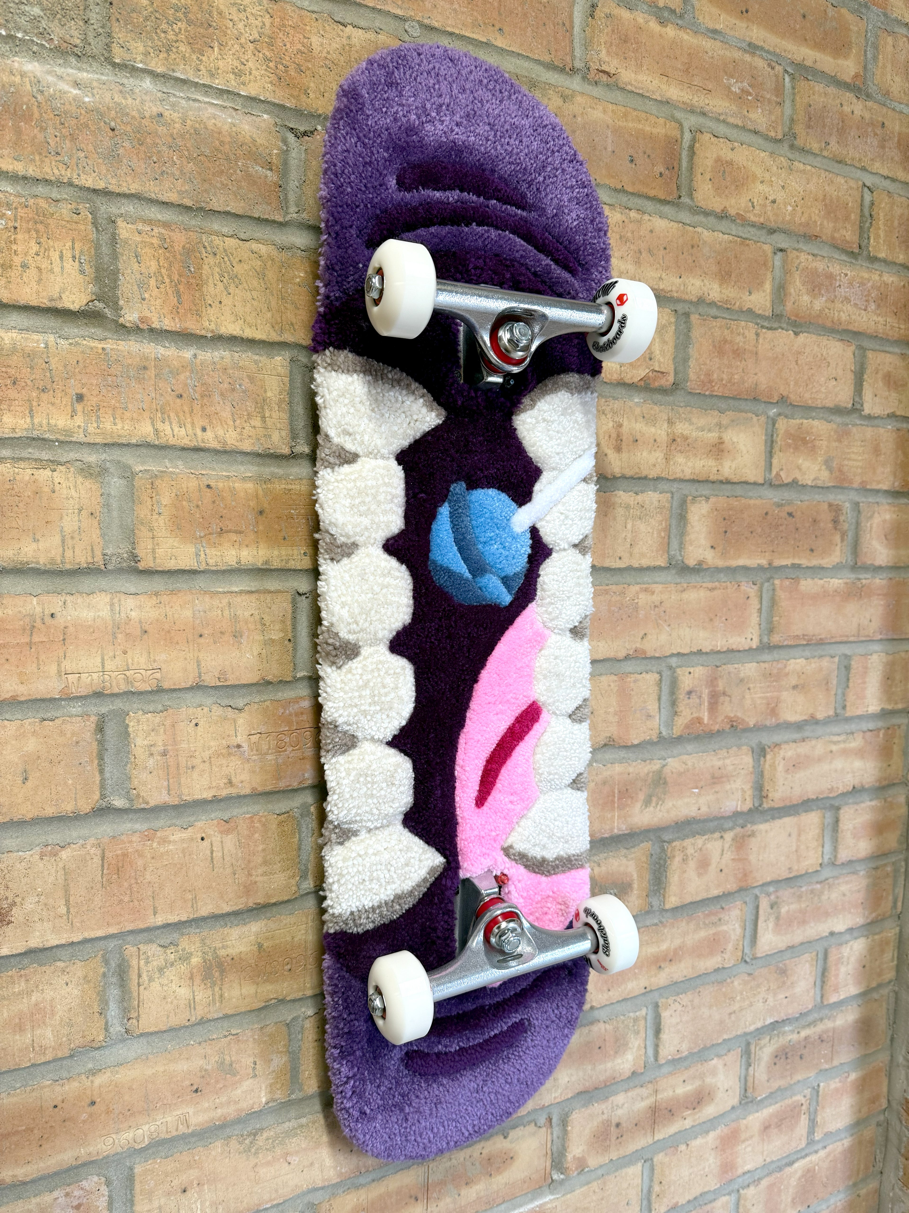 Angled view of the Bad Mouth Rugboard showcasing the dimensional tufted artwork, skateboard deck profile and decorative display design.