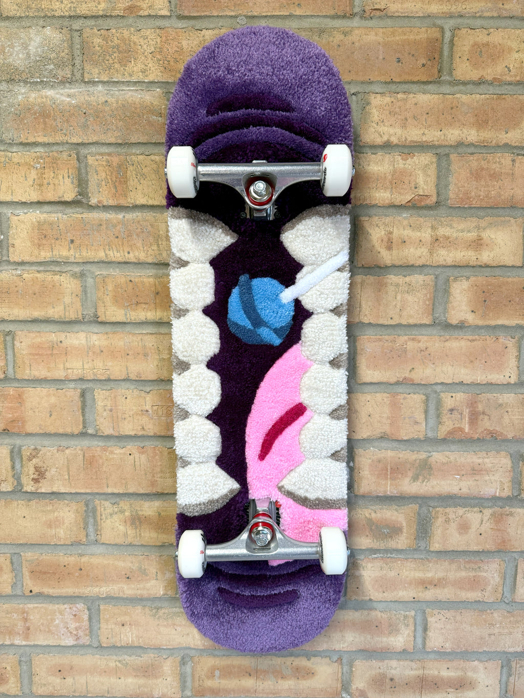 Full view of the Bad Mouth Rugboard featuring a handmade tufted mouth design mounted on a complete skateboard deck with trucks and wheels.