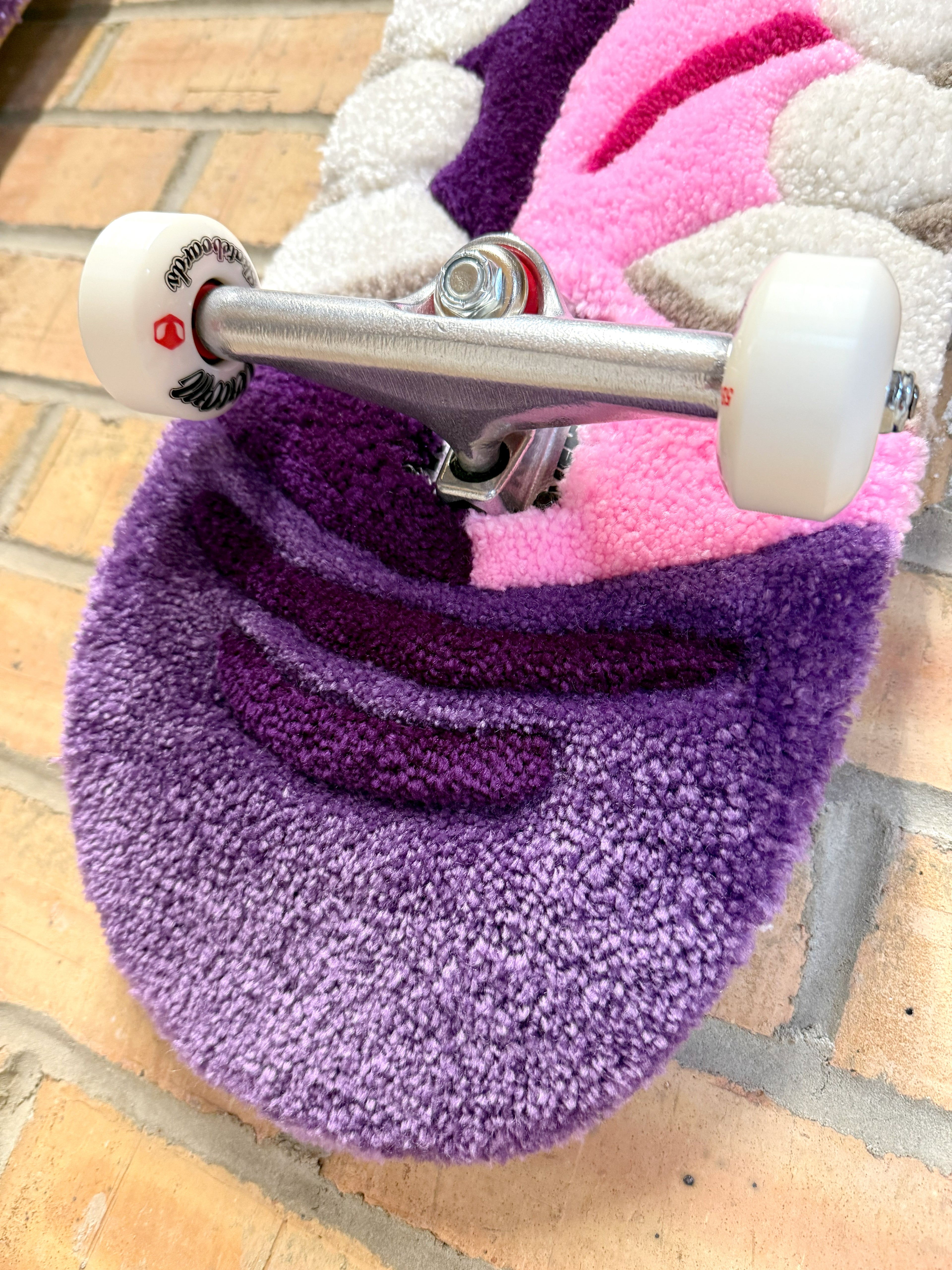 Close-up of the tail section of the Bad Mouth Rugboard highlighting the low-pile tufted texture, skateboard truck and handcrafted finish.