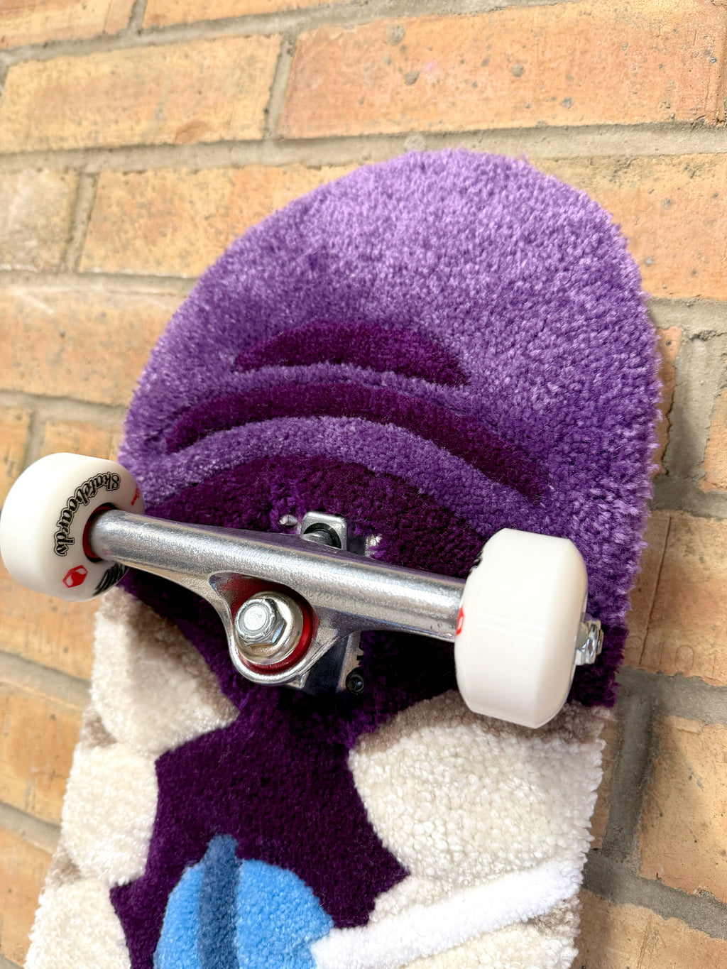 Detailed view of the top section of the Bad Mouth Rugboard showing layered tufting, skateboard hardware and premium handcrafted construction.