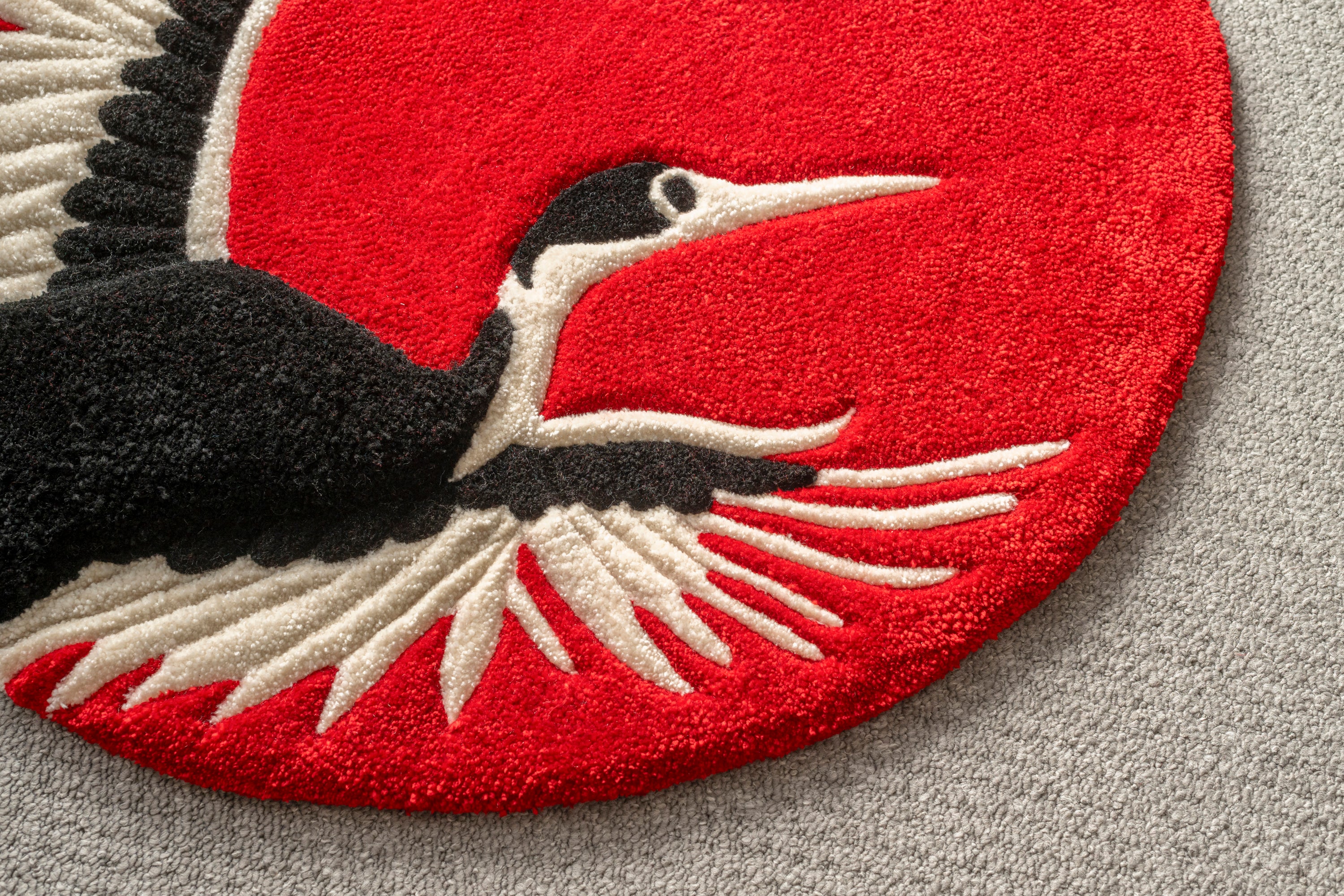 Close-up of the crane head and wings on a handmade Japanese crane rug showcasing detailed tufting and vibrant red background.