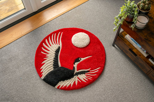 Handmade Japanese crane rug featuring a flying crane against a bold crimson sun with raised moon detail and low-pile tufted finish.