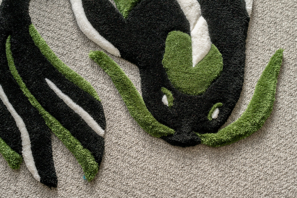 Close-up of a handmade dark green koi fish rug showing textured tufting, sculpted edges and intricate colour transitions.