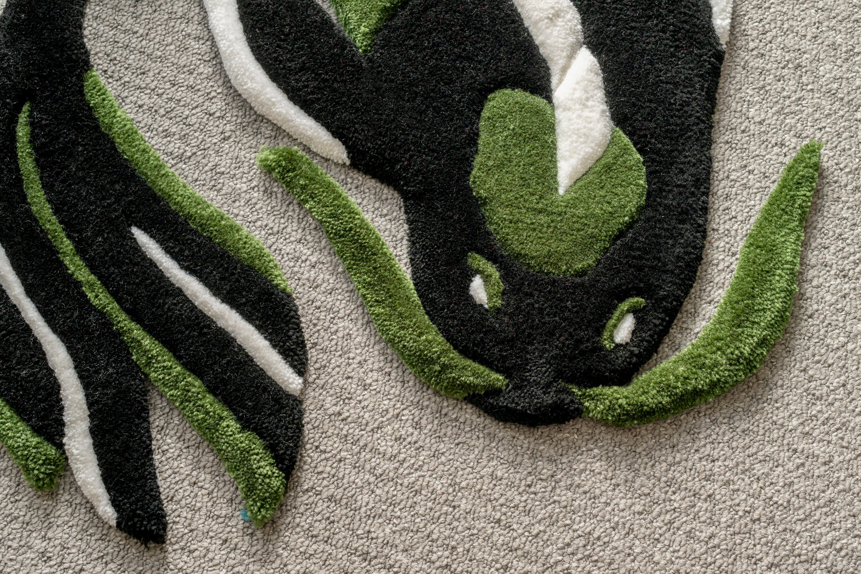 Close-up of a handmade dark green koi fish rug showing textured tufting, sculpted edges and intricate colour transitions.