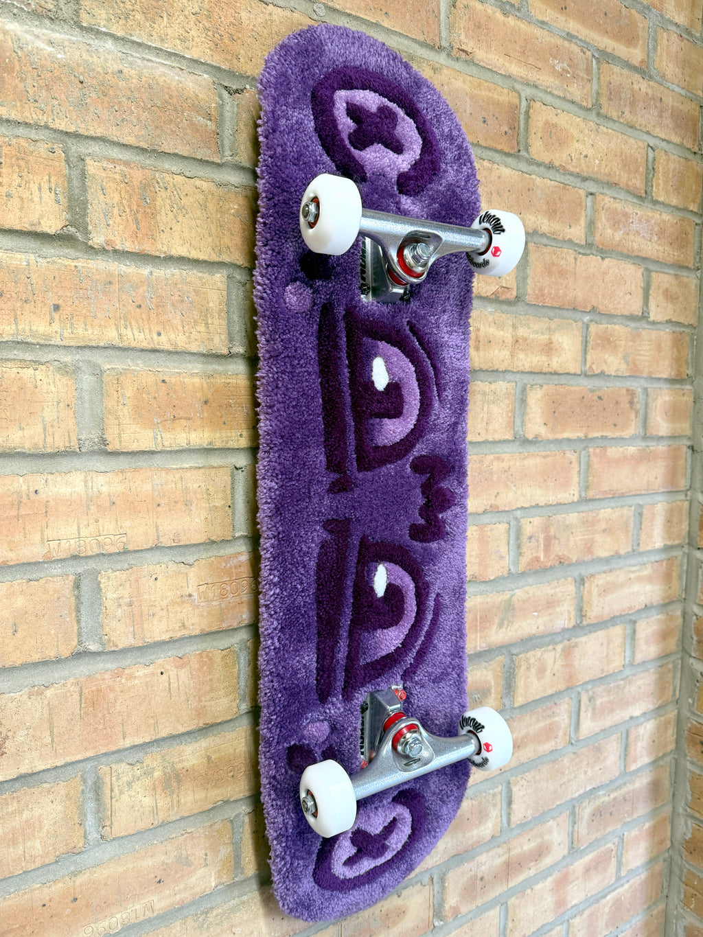 Angled view of the Dirty Look Rugboard showcasing the dimensional tufted artwork, purple eye motif and skateboard deck profile.