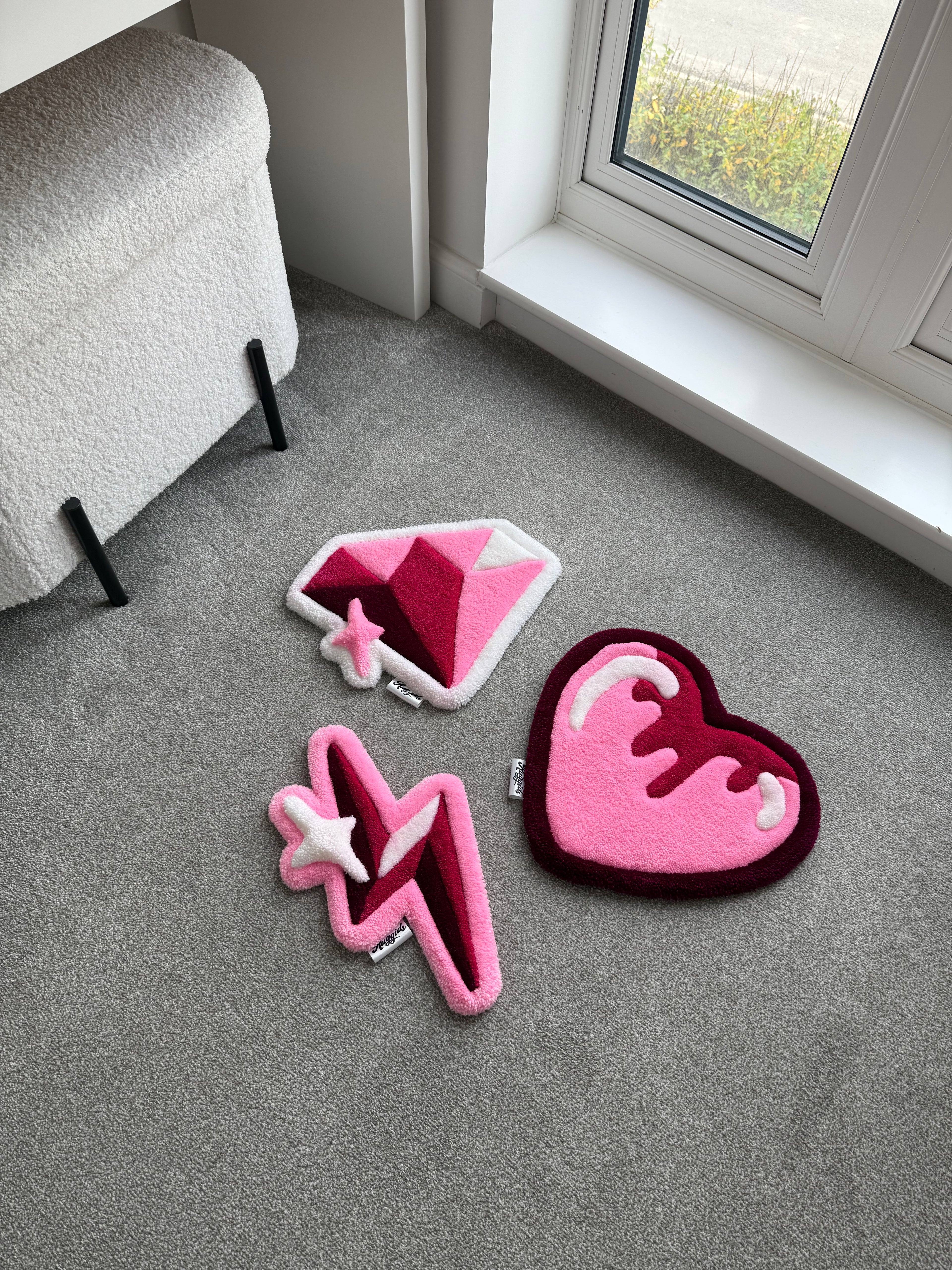 Handmade tufted rug collection featuring a pink heart rug, diamond rug and lightning bolt rug displayed in a bright modern room.