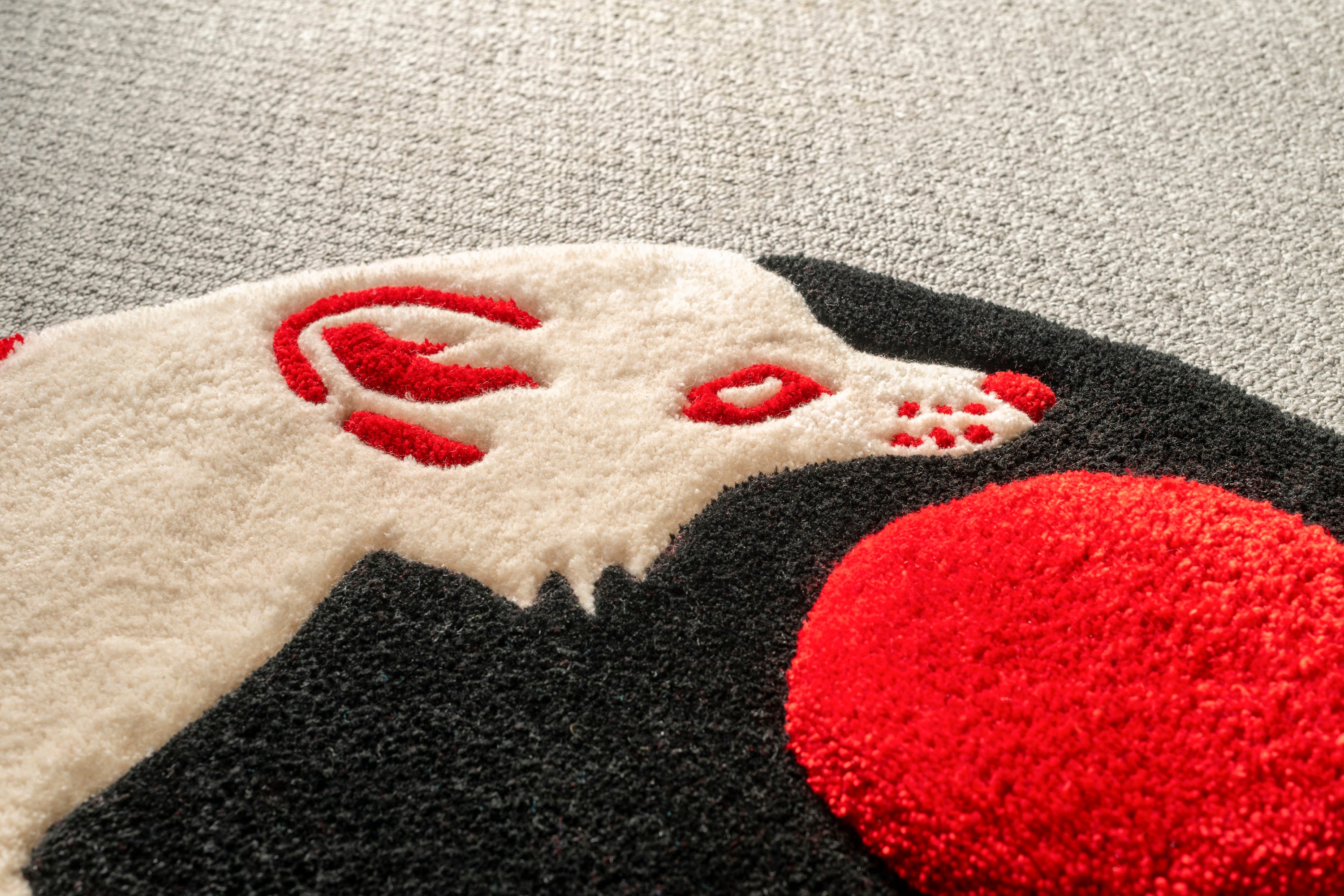 Close-up of the fox head on a handmade kitsune moon rug showing detailed tufting, red accents and soft low-pile texture.