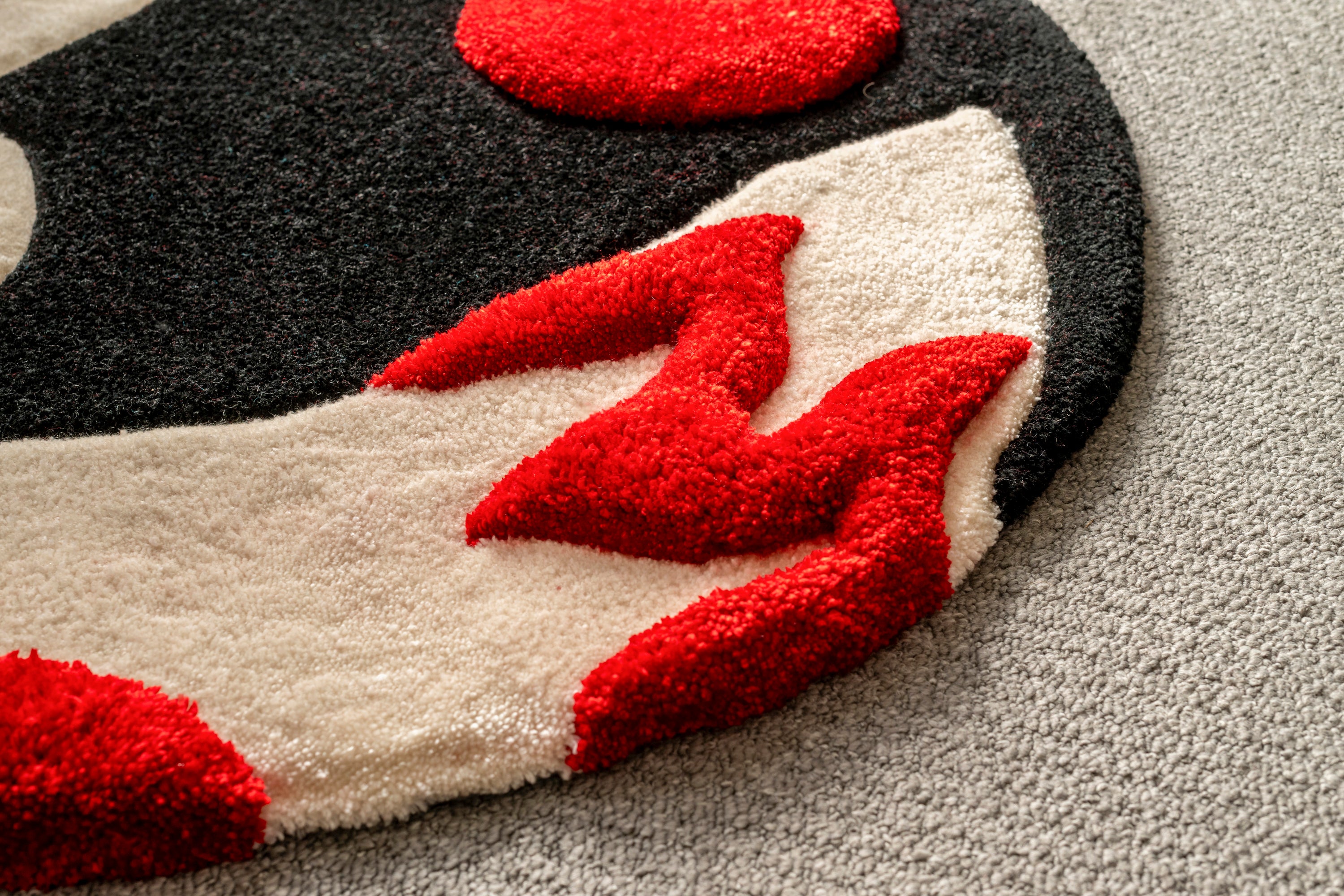 Close-up of the flowing tails on a handmade kitsune moon rug featuring bold red accents and premium tufted texture.