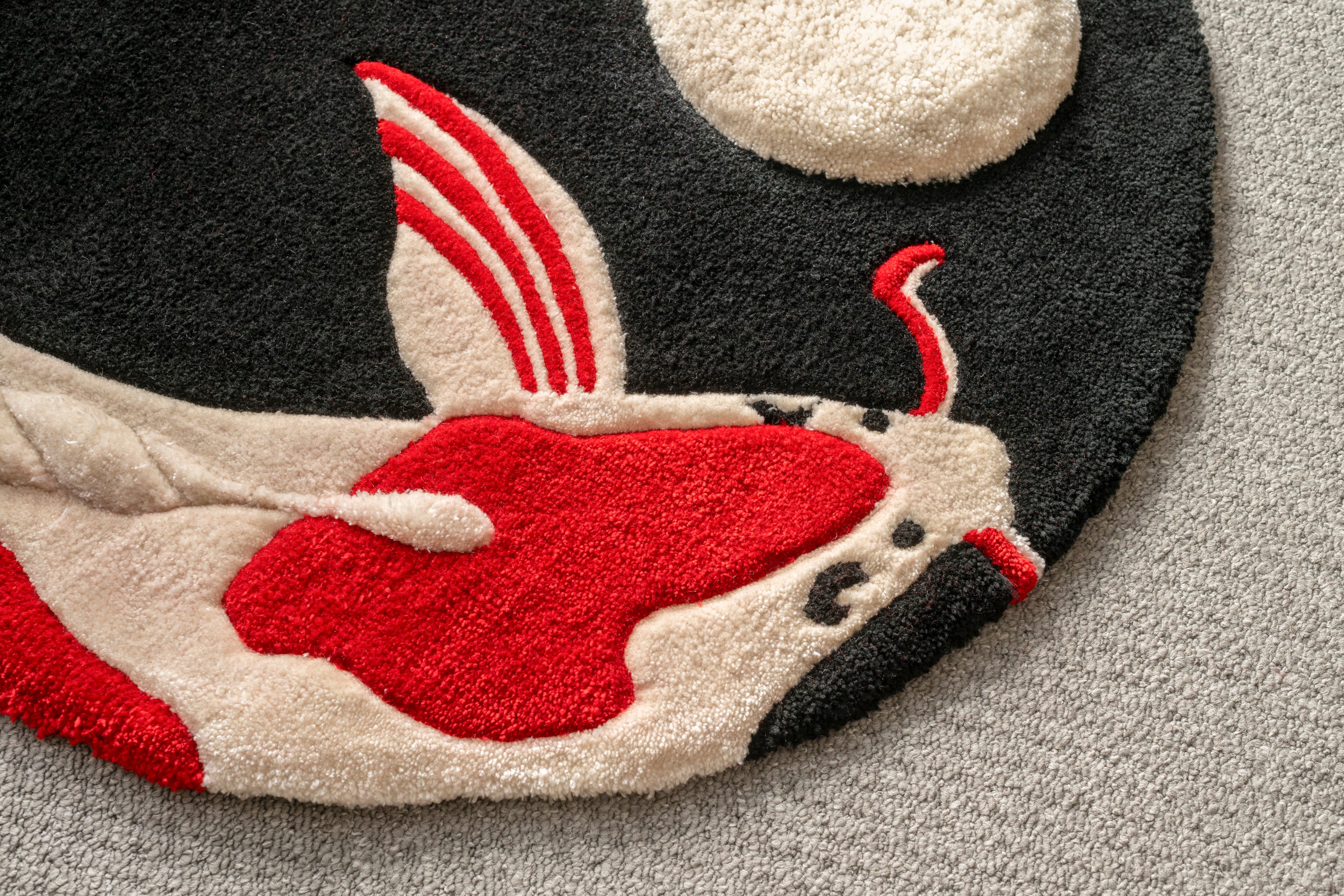 Close-up of the red and cream koi fish design on a handmade Japanese-inspired rug with a textured low-pile finish.