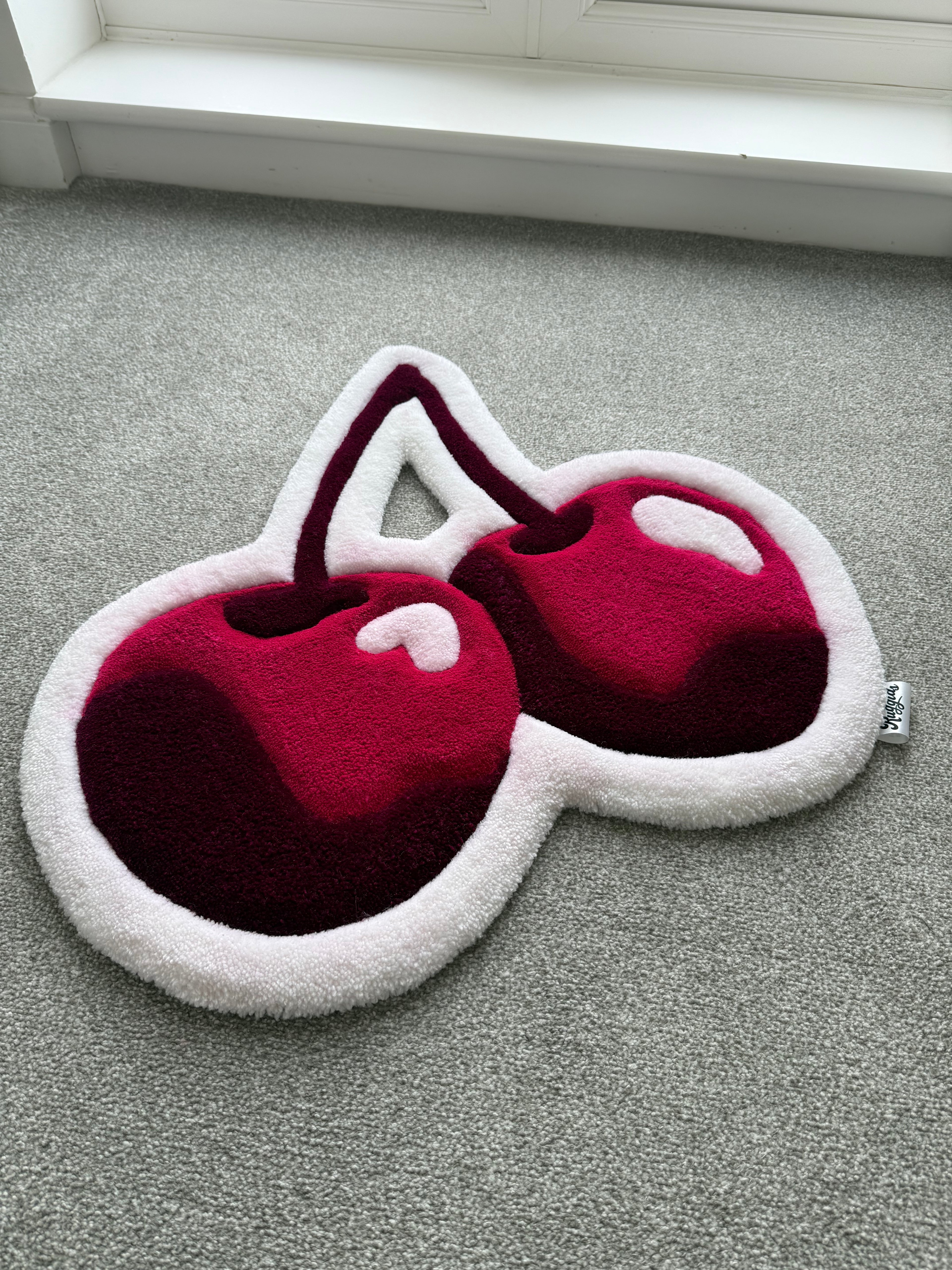 Angled view of a handmade pink cherry rug showcasing its sculpted shape, soft acrylic yarn and layered tufted details.