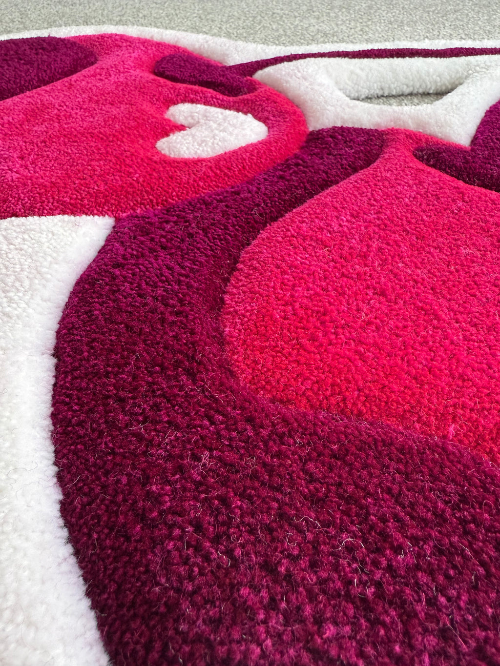 Close-up detail of a handmade pink cherry rug highlighting premium tufting, soft acrylic yarn and rich pink colour gradients.