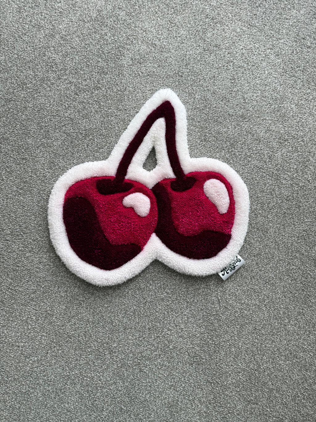 Handmade pink cherry rug featuring two glossy cherries in pink, burgundy and white with a soft low-pile finish.