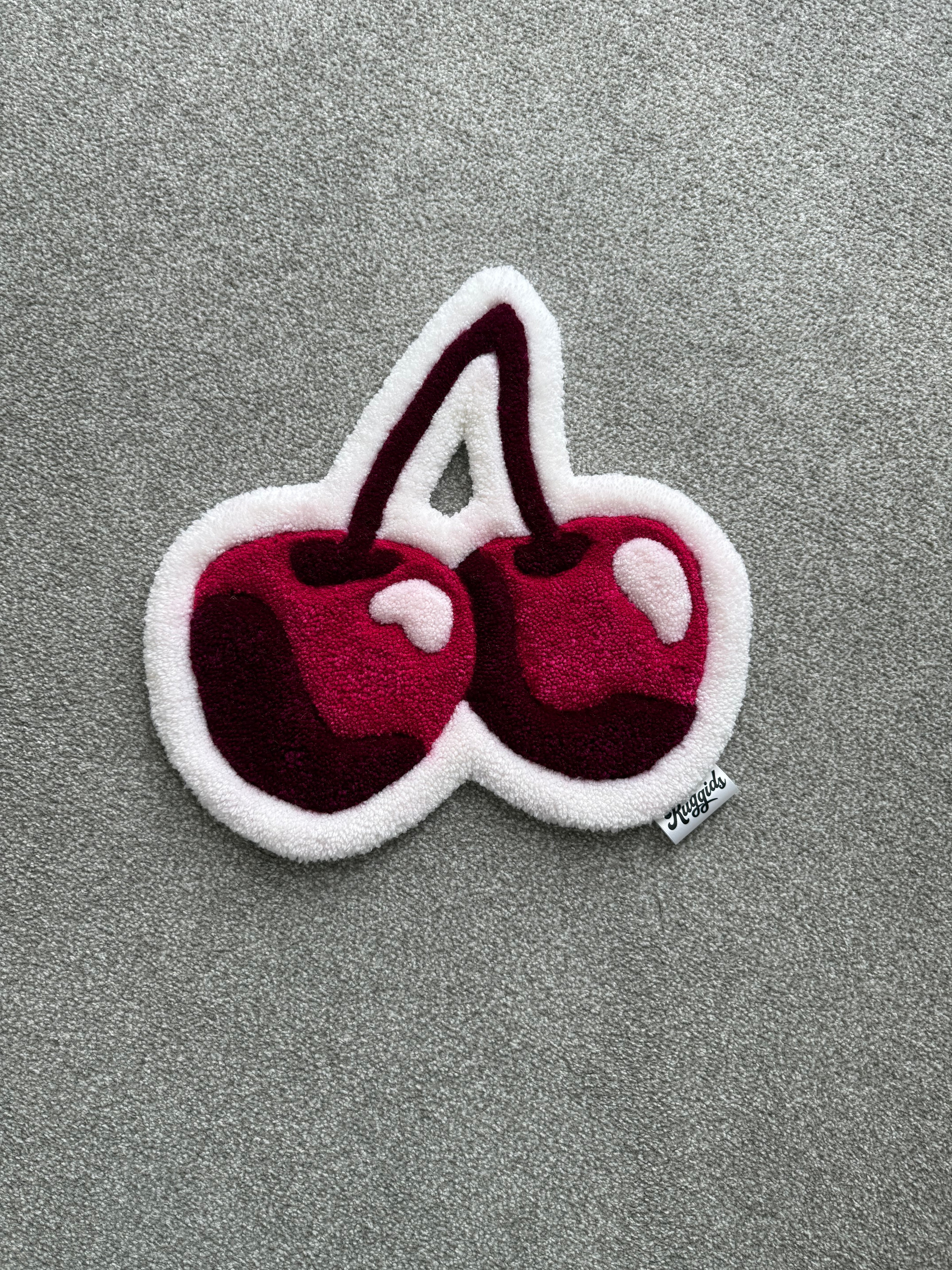 Handmade pink cherry rug featuring two glossy cherries in pink, burgundy and white with a soft low-pile finish.
