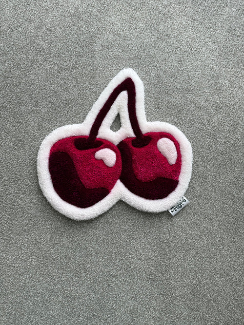 Handmade pink cherry rug featuring two glossy cherries in pink, burgundy and white with a soft low-pile finish.