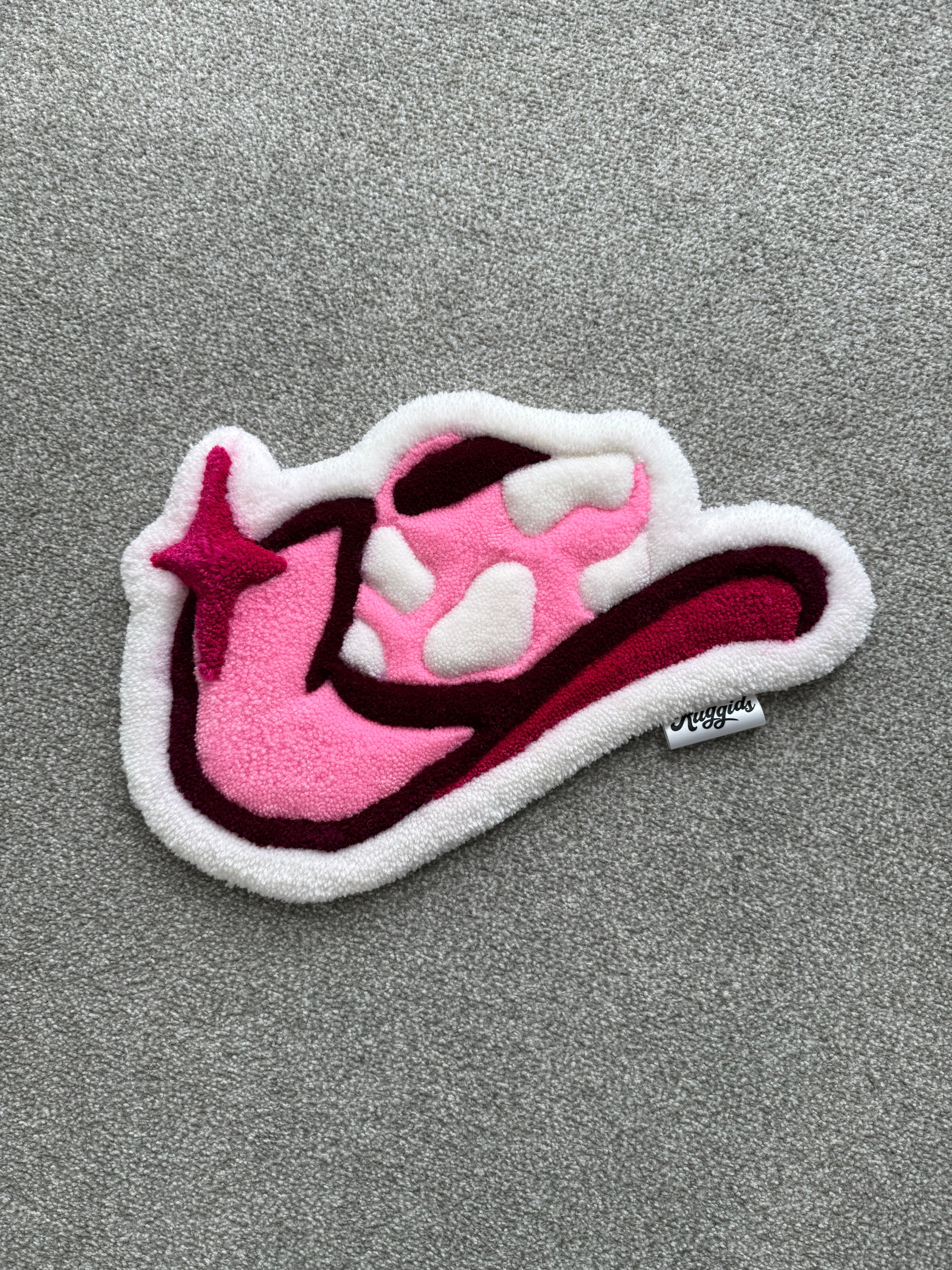 Handmade pink cowgirl hat rug featuring a western-inspired design with white cow print details and deep pink accents.