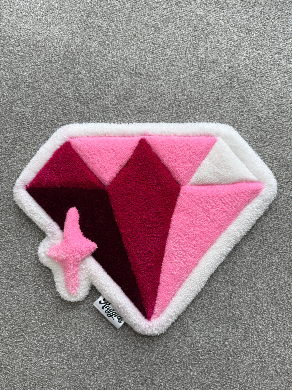 Handmade pink diamond rug featuring layered pink, burgundy and white geometric facets with a sparkling star detail.