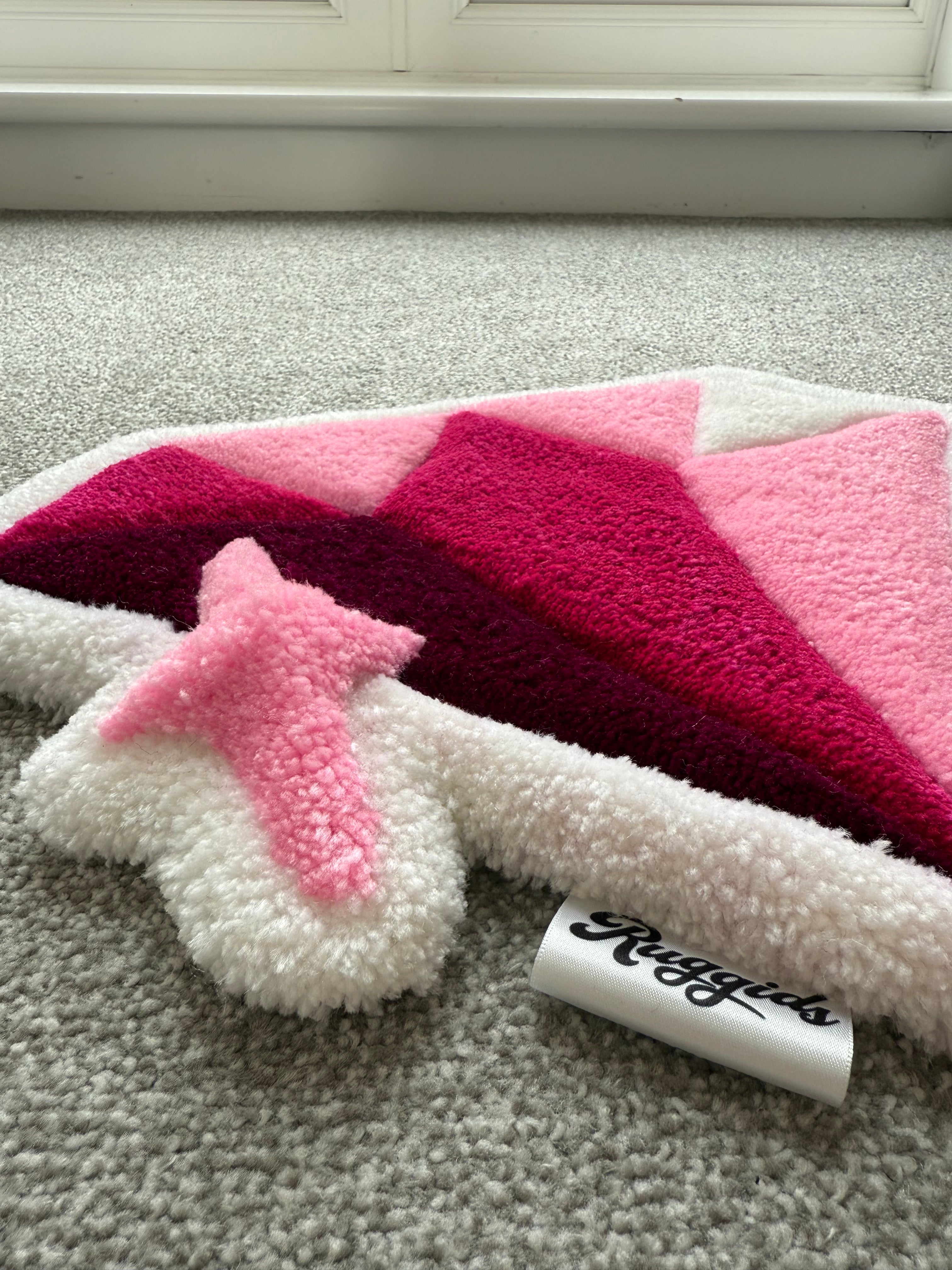 Low-angle view of a handmade pink diamond rug showcasing its low-pile texture, dimensional design and soft acrylic yarn.