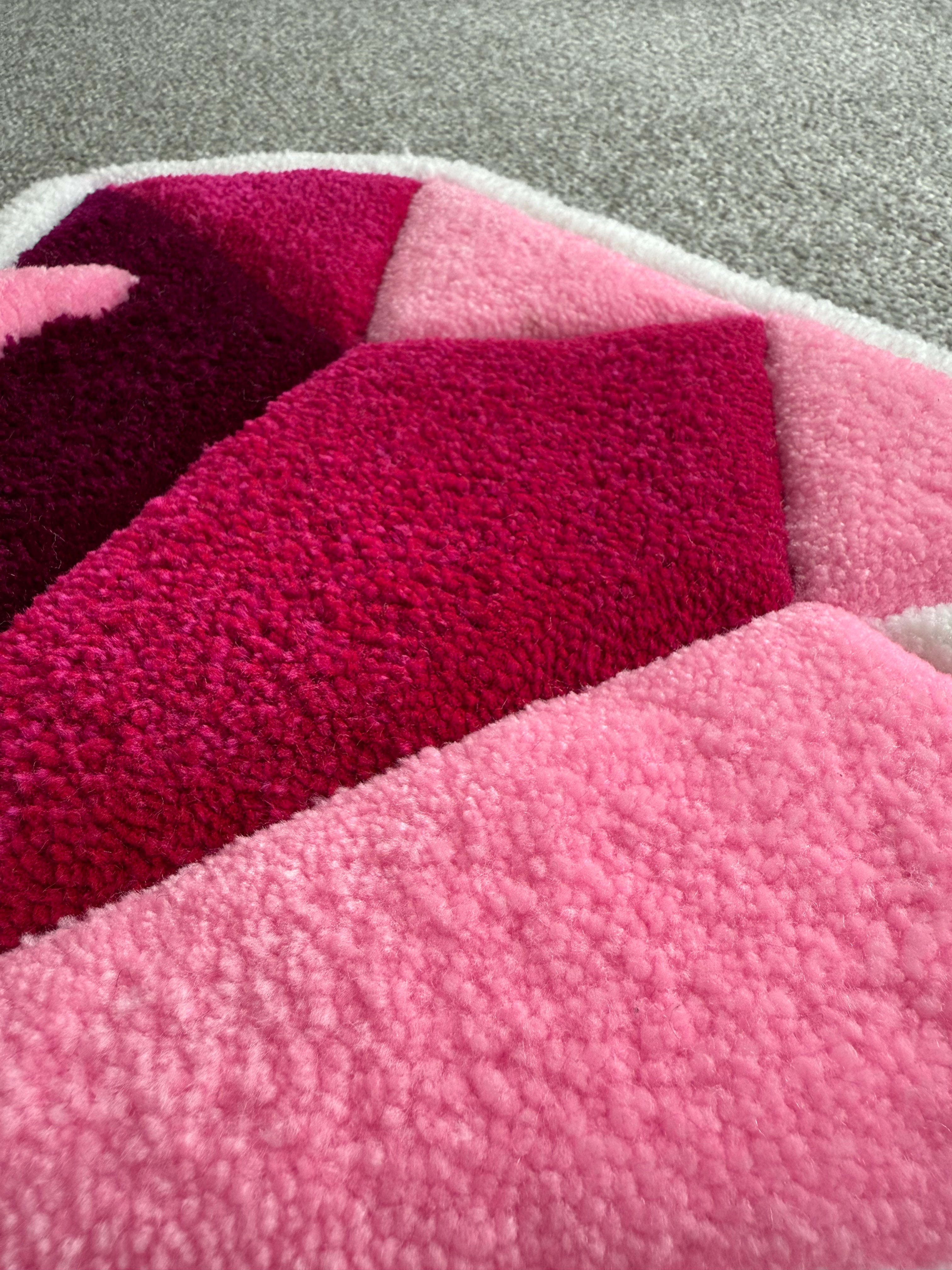 Close-up detail of a pink diamond rug highlighting premium tufting, geometric shaping and soft pink acrylic yarn.