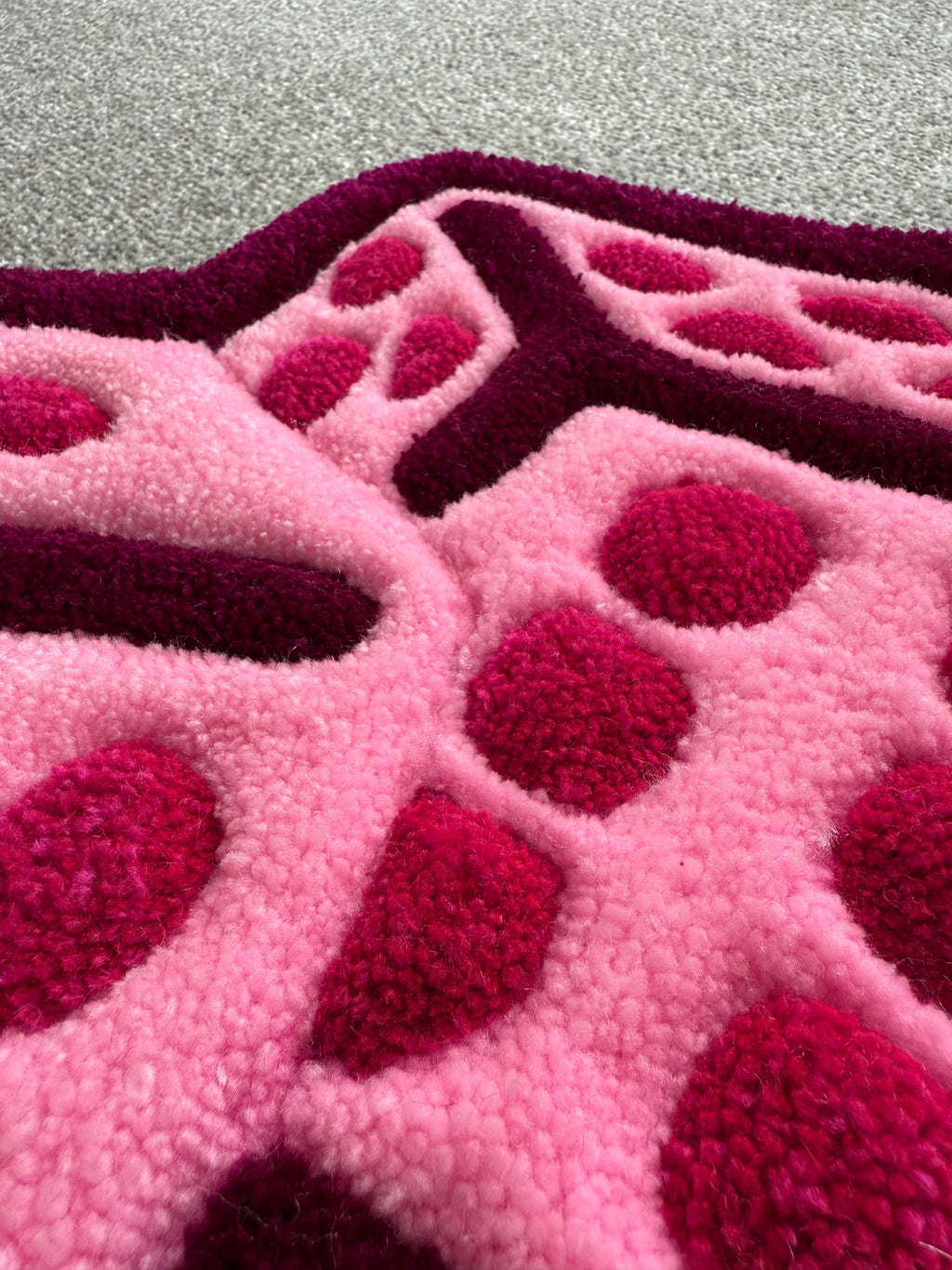 Close-up of the pink dice rug showing detailed tufting, raised dice markings and soft low-pile acrylic yarn texture.