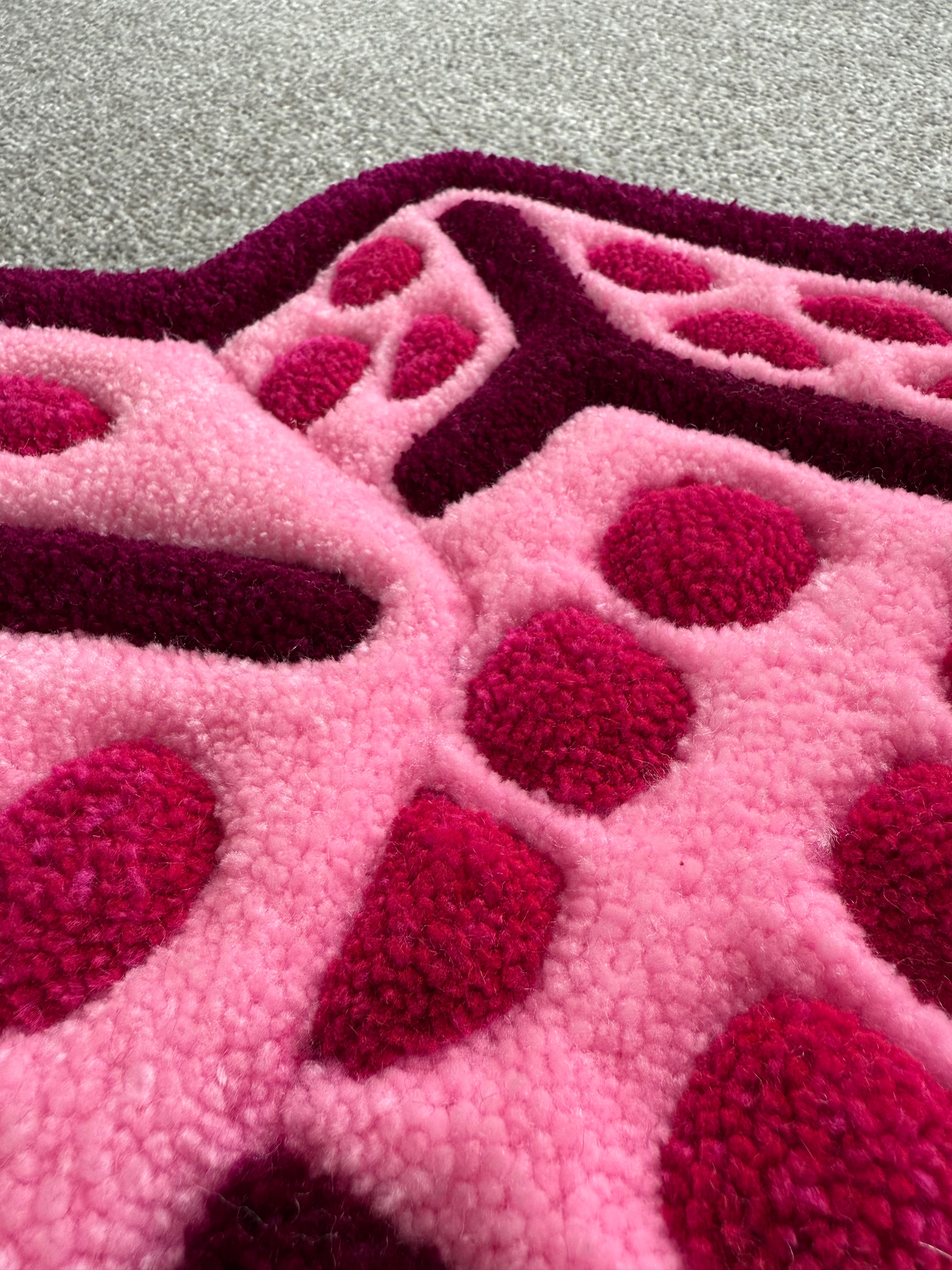 Close-up of the pink dice rug showing detailed tufting, raised dice markings and soft low-pile acrylic yarn texture.