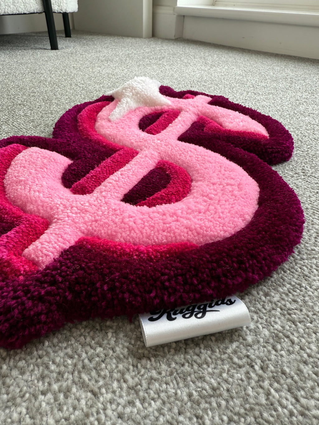 Angled view of a pink dollar sign rug showcasing dimensional tufting, soft acrylic yarn and handcrafted detailing.