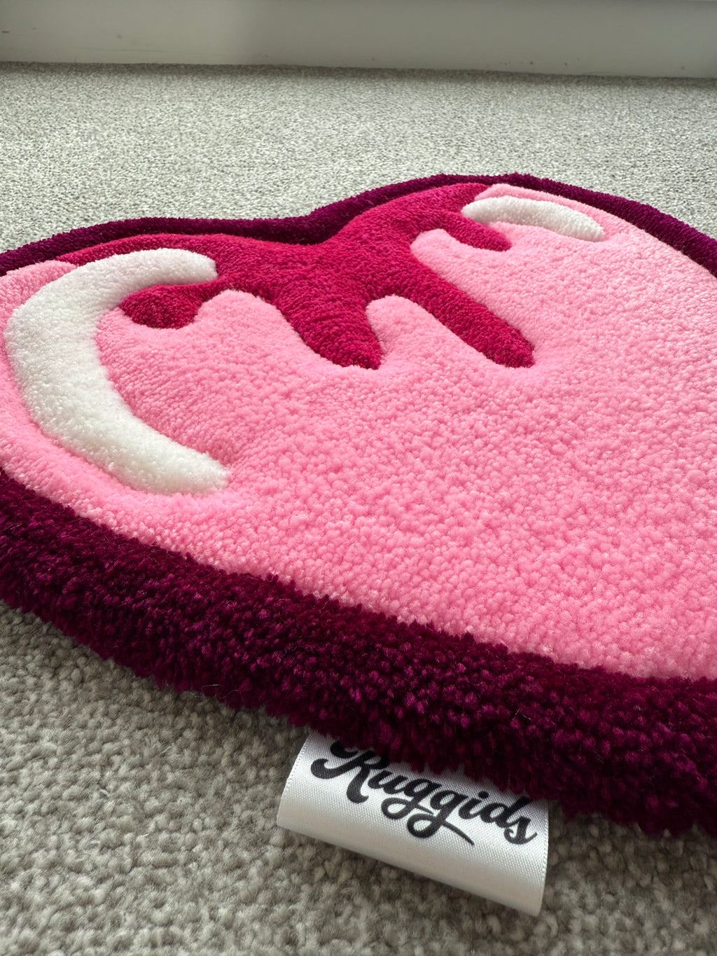 Angled view of the pink heart rug showcasing the dimensional tufted details, soft acrylic yarn texture and handcrafted construction.