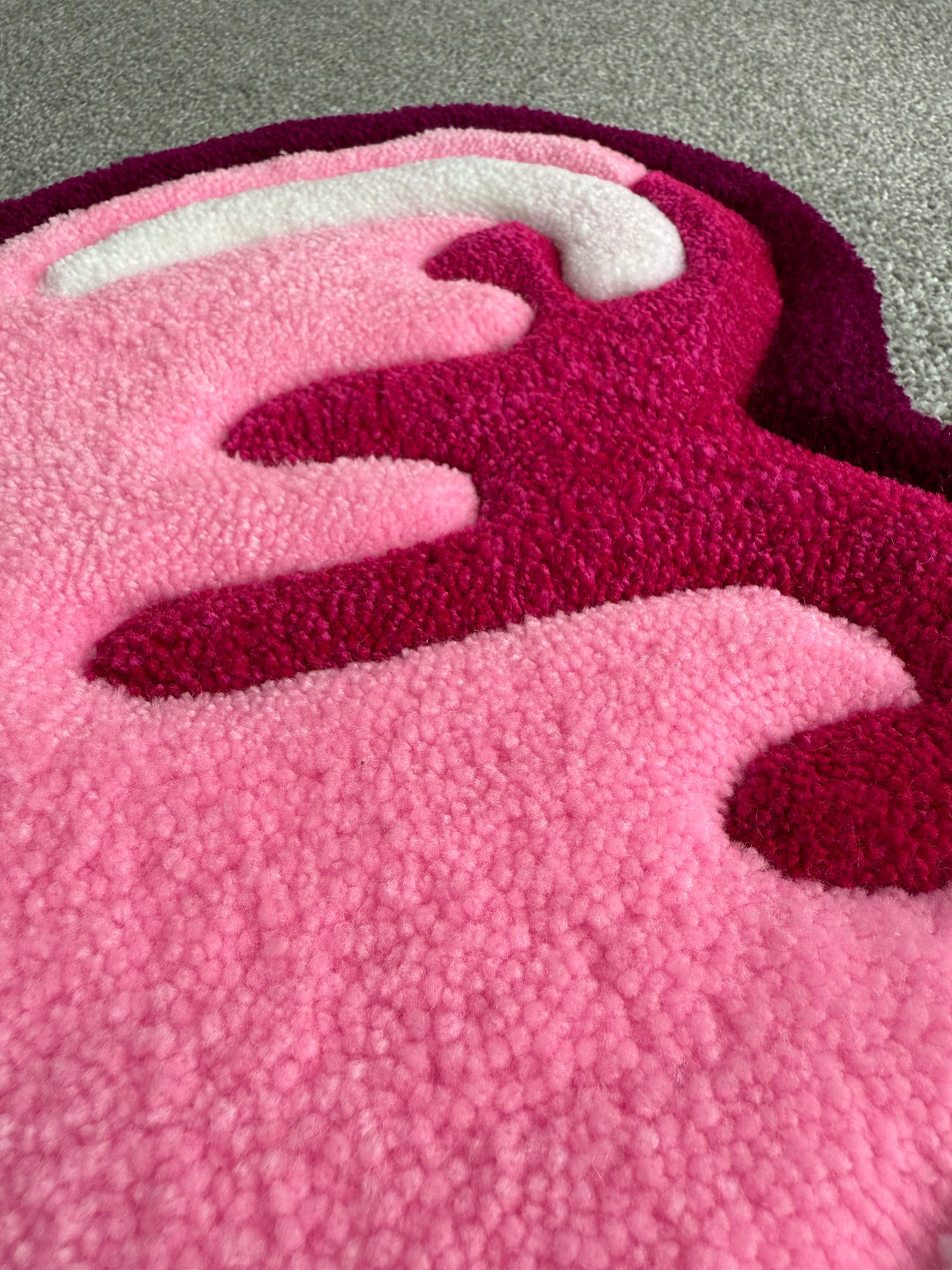 Close-up of the handmade pink heart rug highlighting the raised tufted icing design, layered colours and low-pile texture.