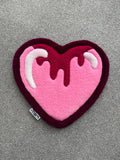 Handmade pink heart rug featuring a dripping icing-inspired design in shades of pink, burgundy and white with a low-pile tufted finish.