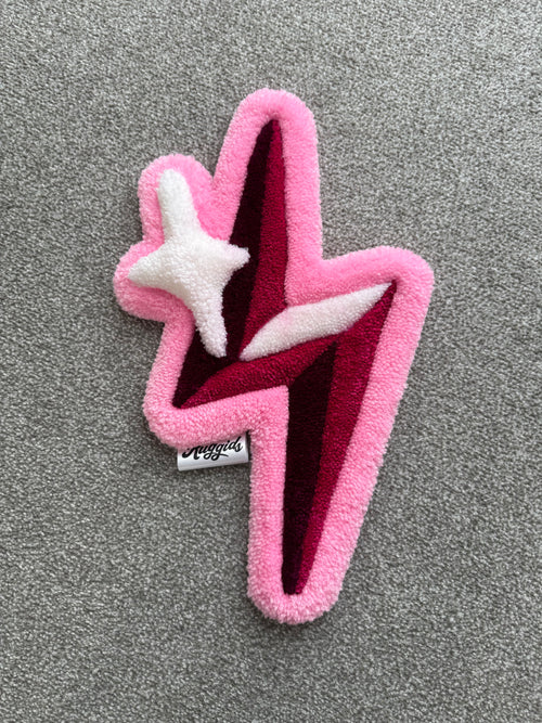 Handmade pink lightning bolt rug featuring layered pink, burgundy and white accents with a sparkling star detail.