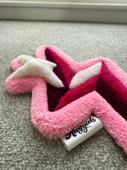 Low-angle view of a handmade pink lightning bolt rug showcasing its low-pile texture, raised details and soft acrylic yarn.
