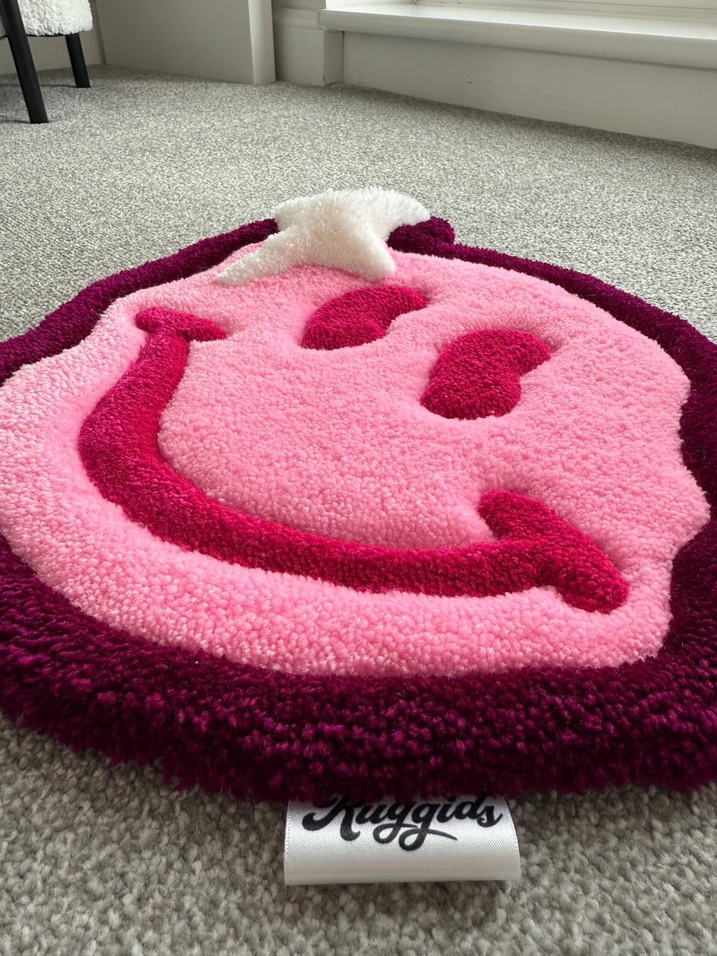 Angled view of the pink smiley face rug showcasing its dimensional tufted design, soft texture and handcrafted construction.