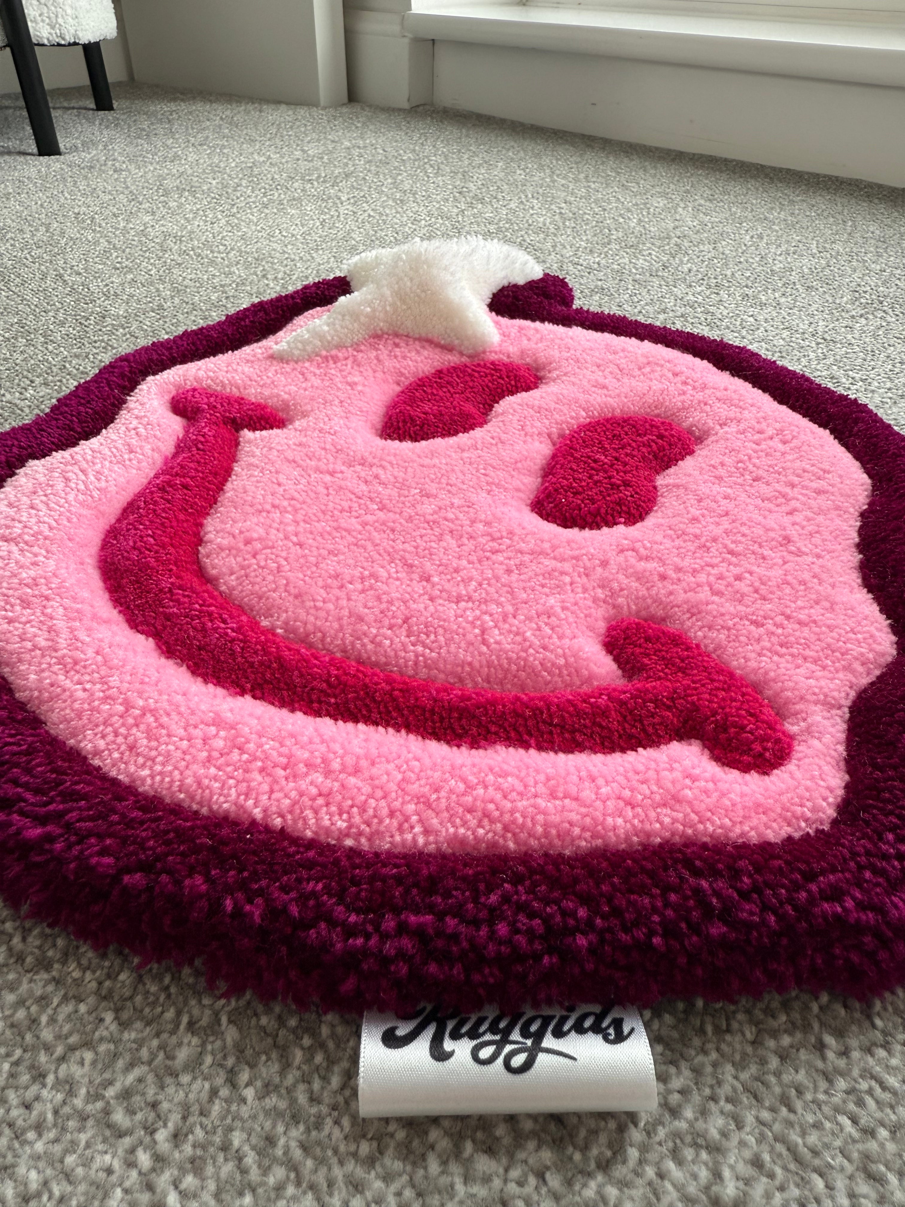 Angled view of the pink smiley face rug showcasing its dimensional tufted design, soft texture and handcrafted construction.