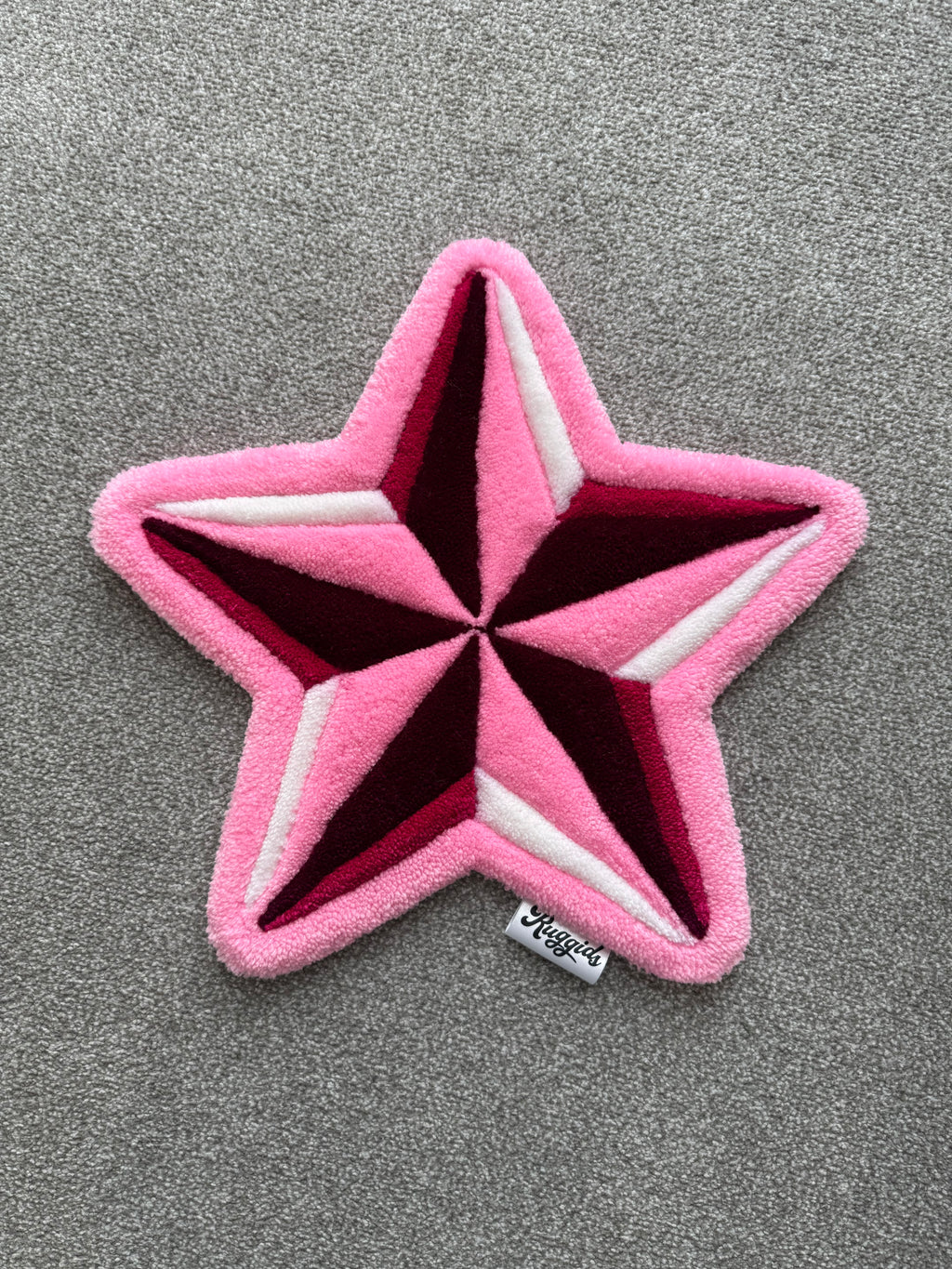 Handmade pink star rug featuring a bold five-point star design with layered pink, burgundy and white details.