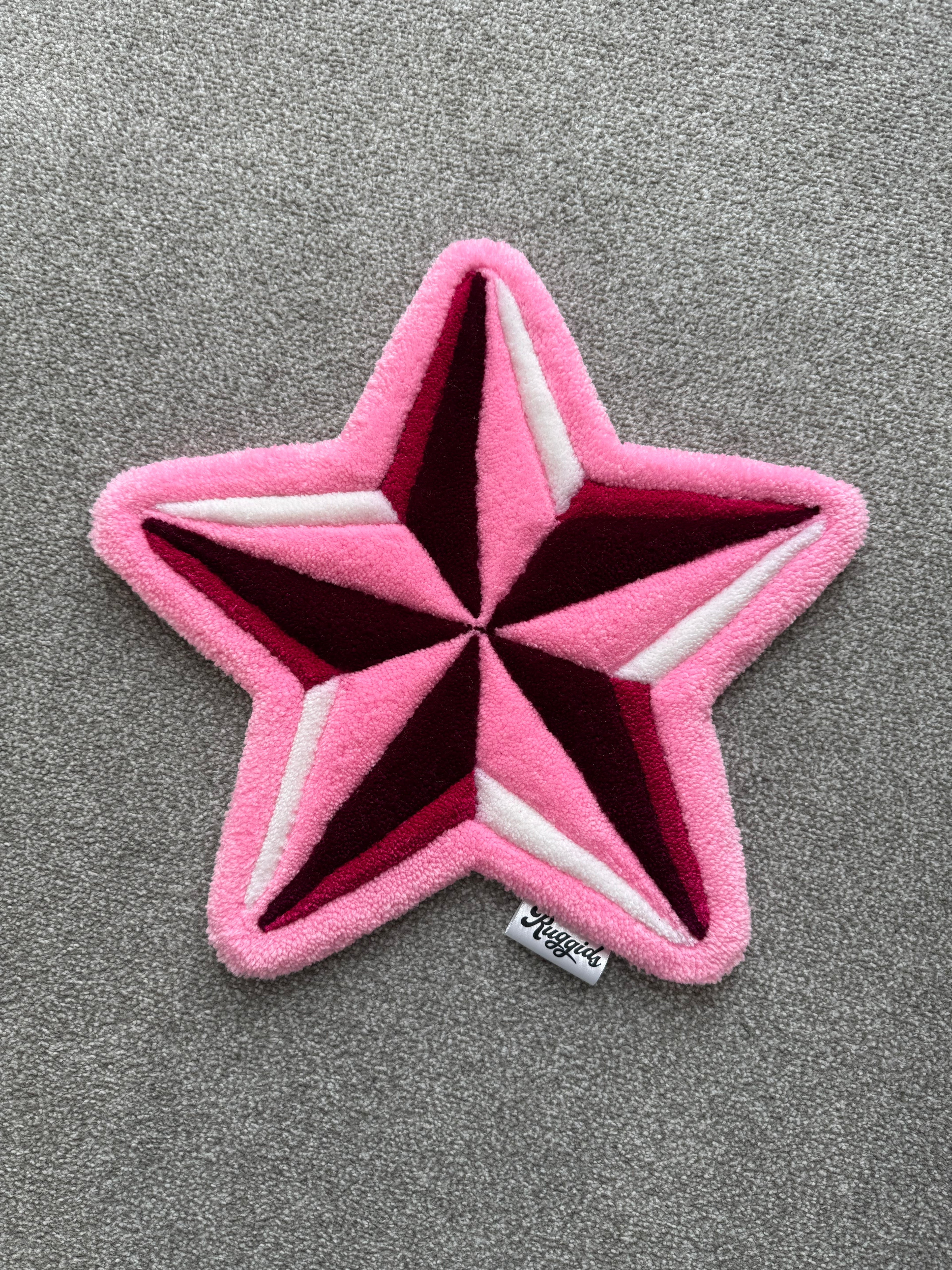 Handmade pink star rug featuring a bold five-point star design with layered pink, burgundy and white details.