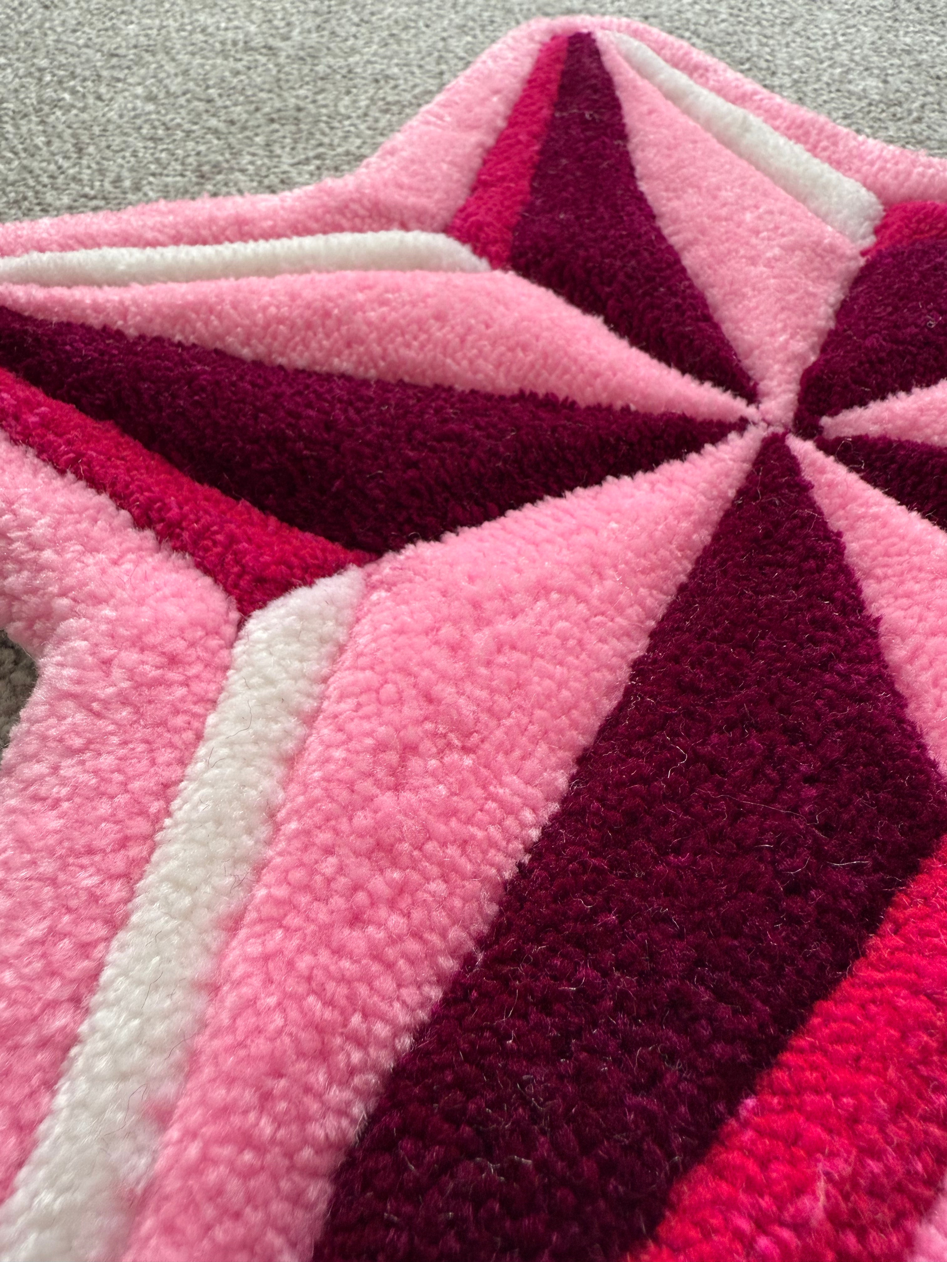 Close-up detail of a pink star rug highlighting premium acrylic yarn, clean tufting lines and layered colour sections.