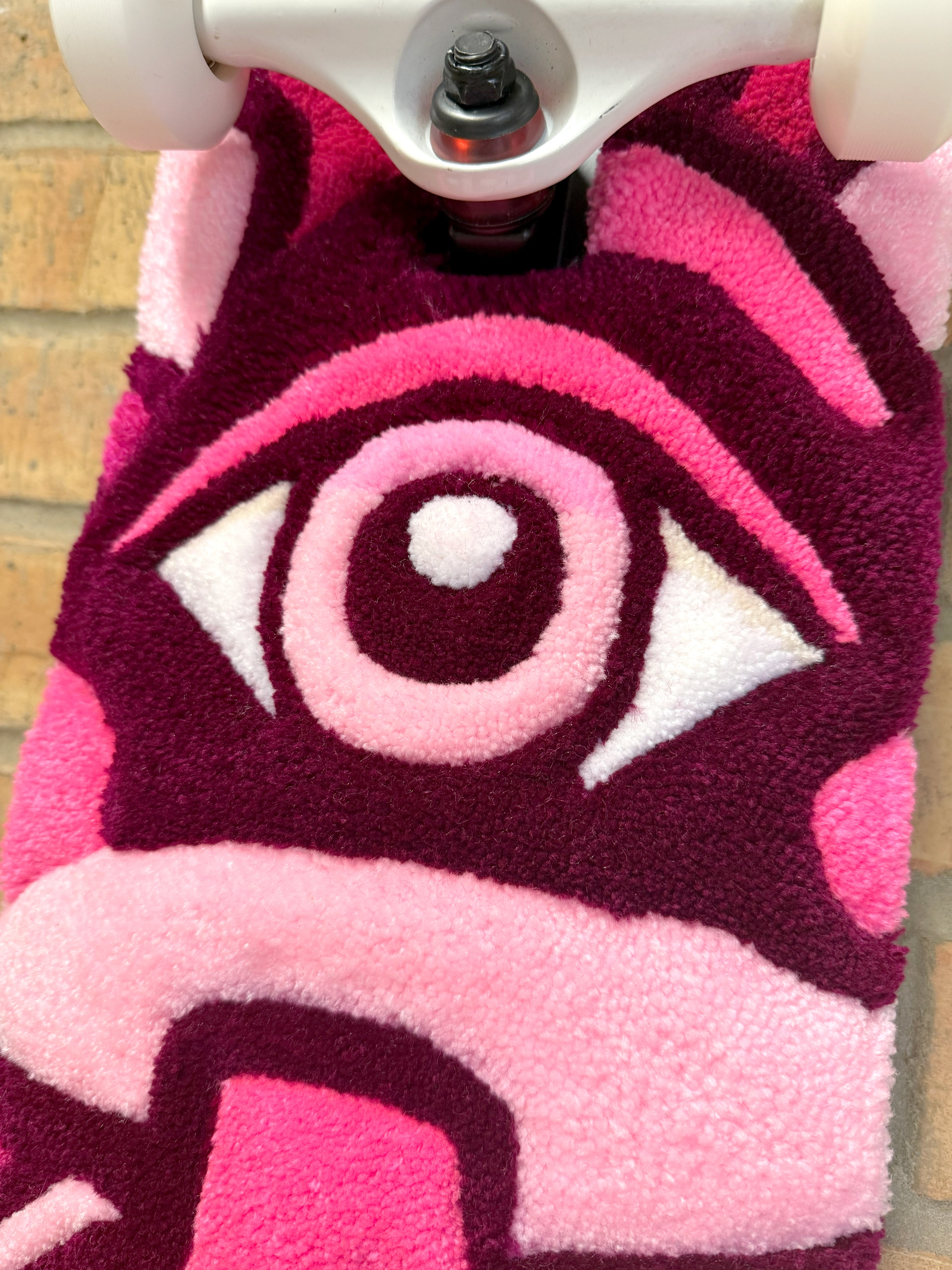 Close-up photograph of the tufted eye detail on the Psychedelic Mushroom Rugboard in pink, burgundy, and white.