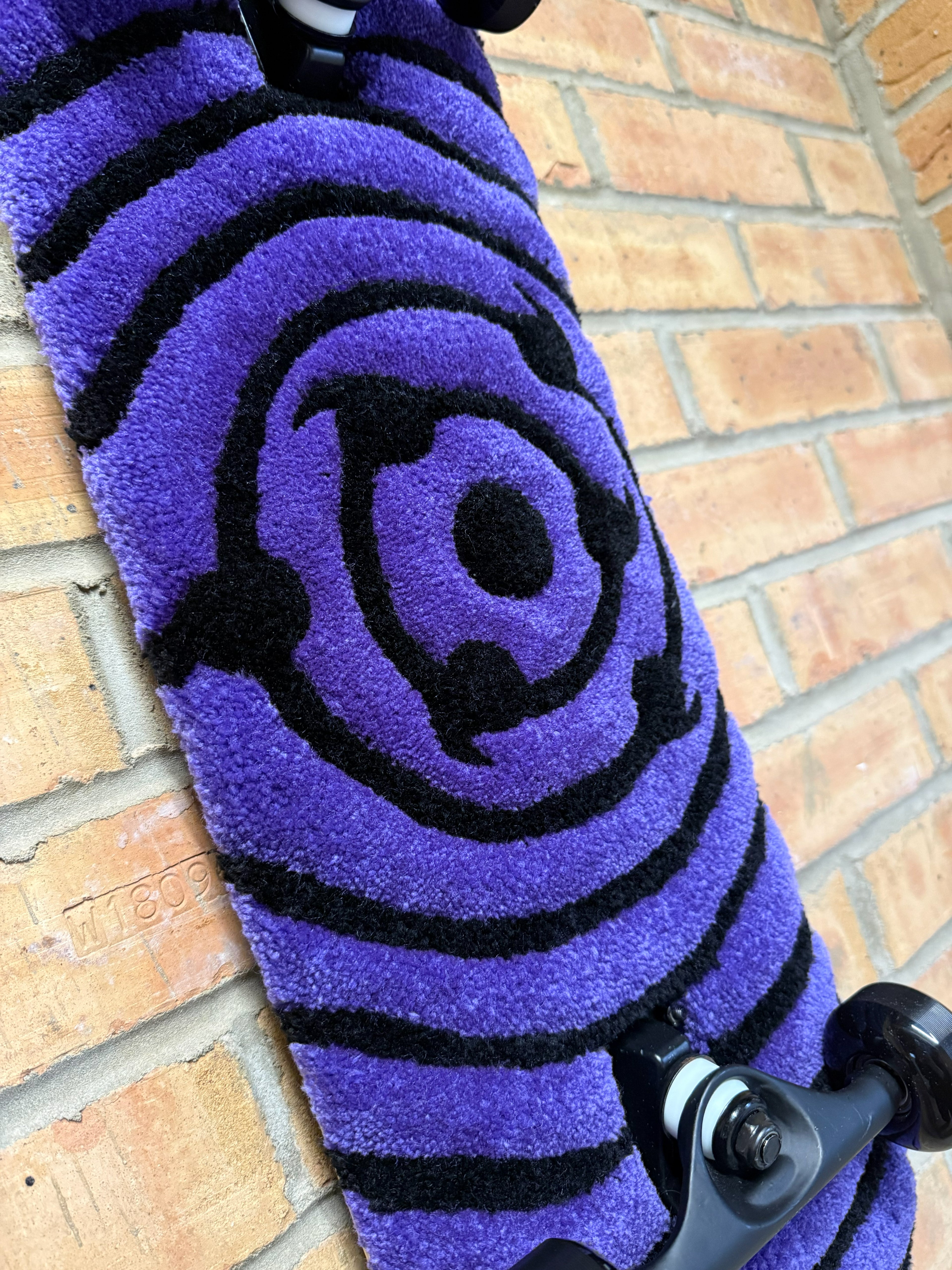 Close-up of the Ripple Eye Rugboard eye design showing hand-tufted texture and black ripple detailing on a purple background