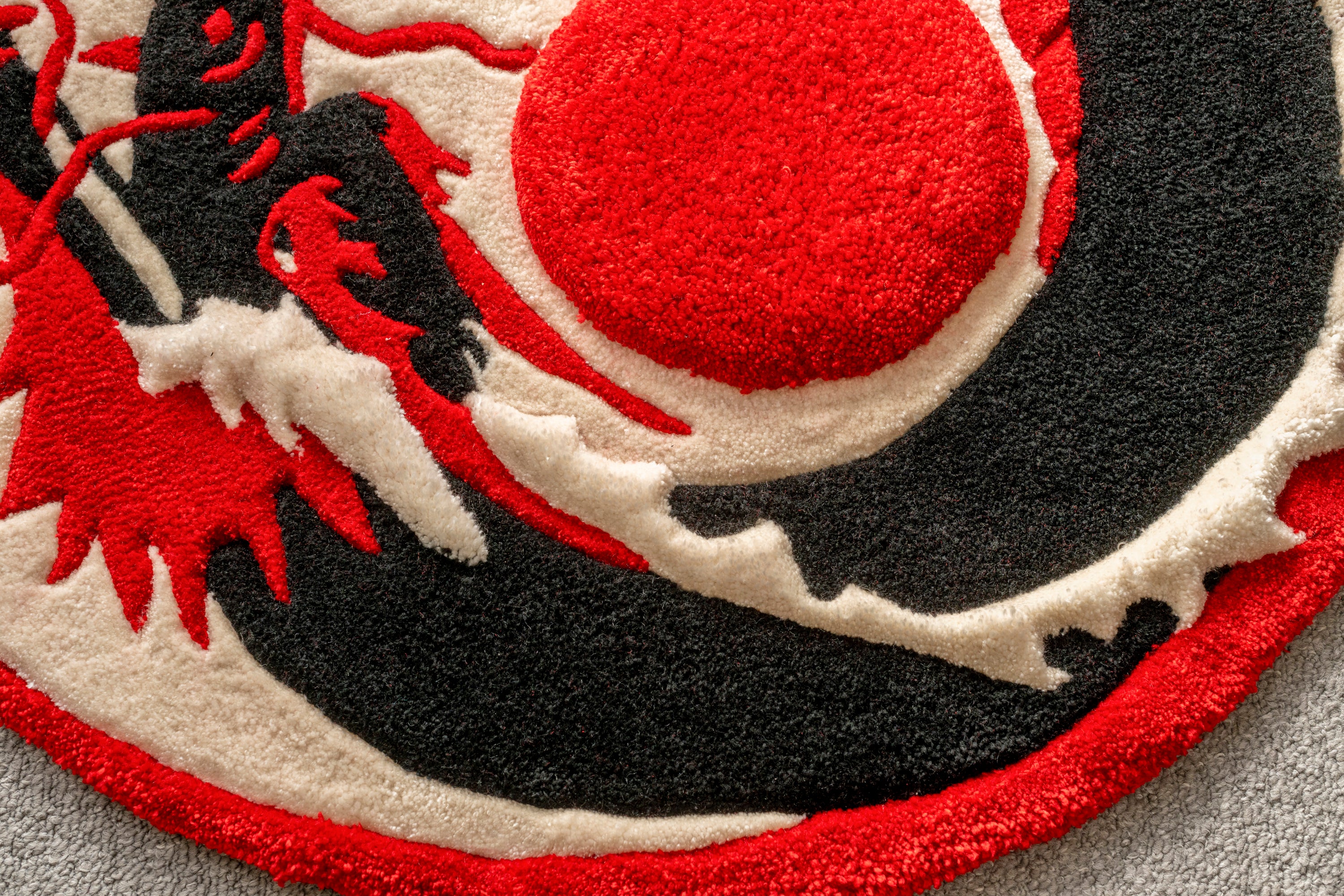 Detailed view of the raised crimson sun and dragon elements on a handmade Japanese dragon rug.