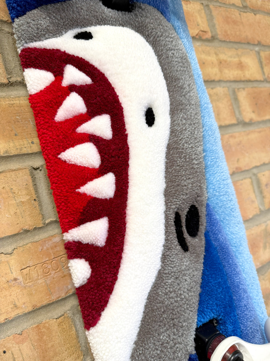 Close-up of the Shark Rugboard featuring the shark graphic, red mouth detail, and hand-tufted texture