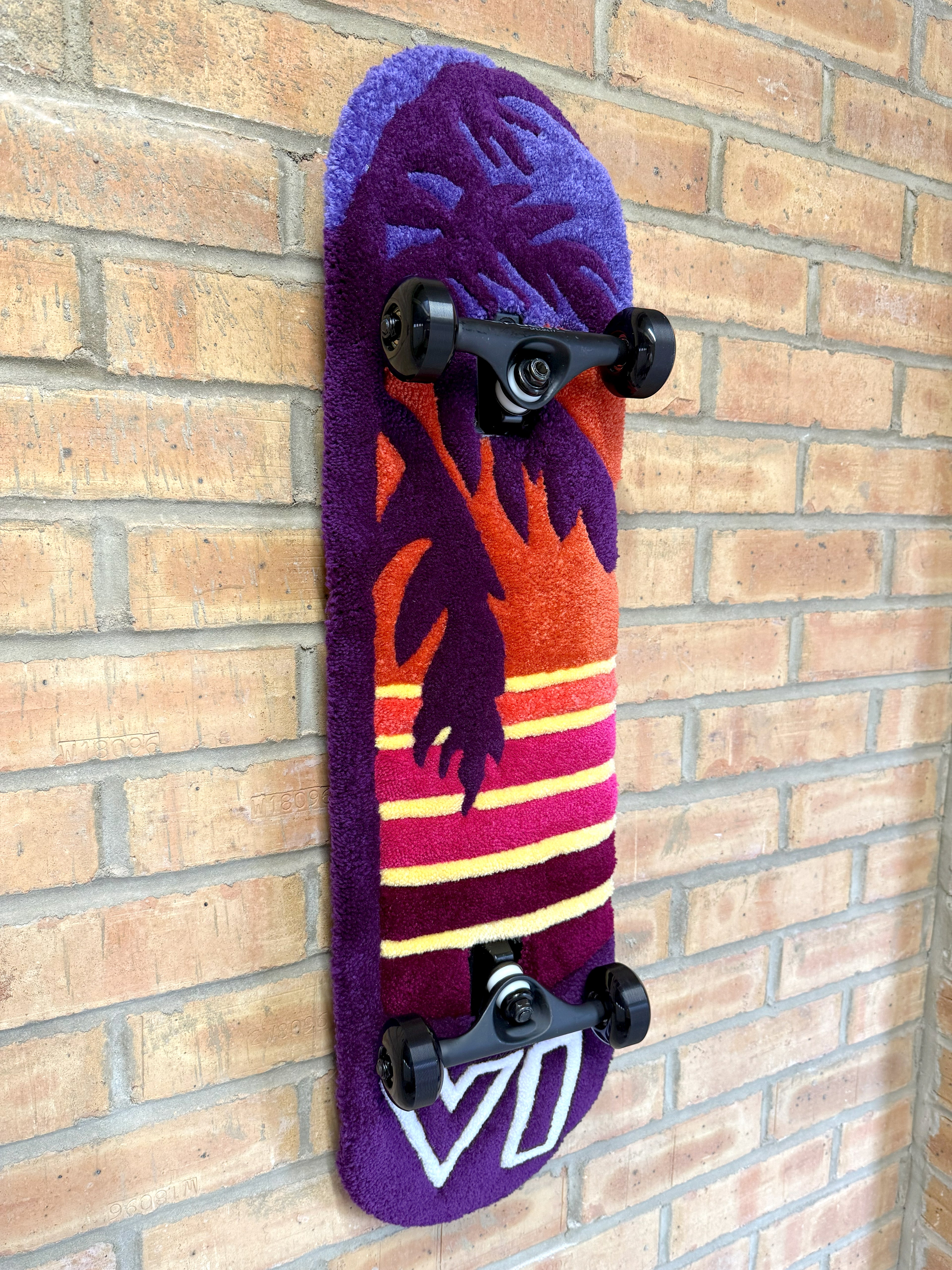 Angled view of the handmade Vice Sunset Rugboard highlighting the palm tree silhouette, retro sunset stripes and tufted texture.