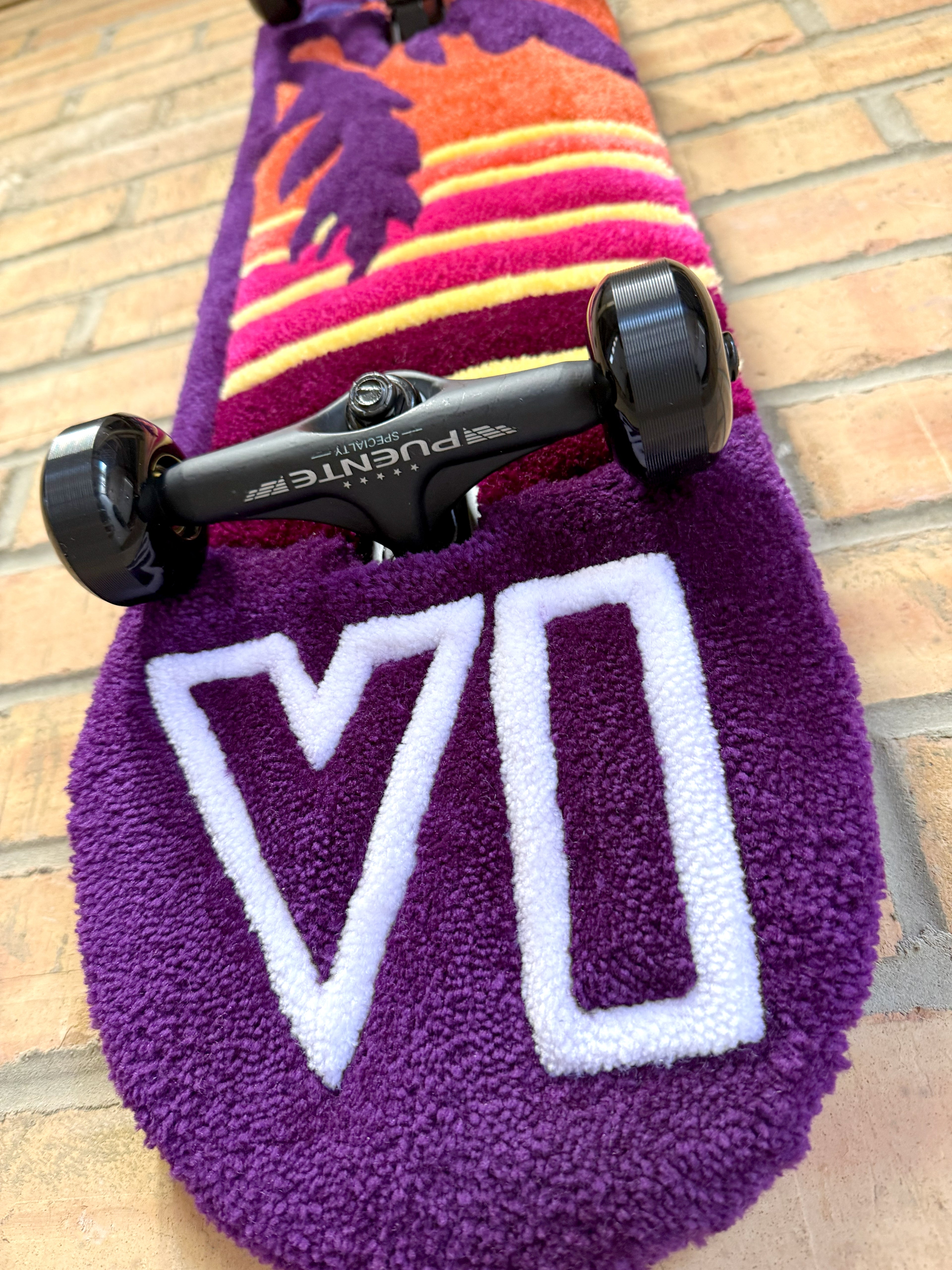 Close-up of the Vice logo on the handmade Vice Sunset Rugboard showing tufted texture and purple colour tones.