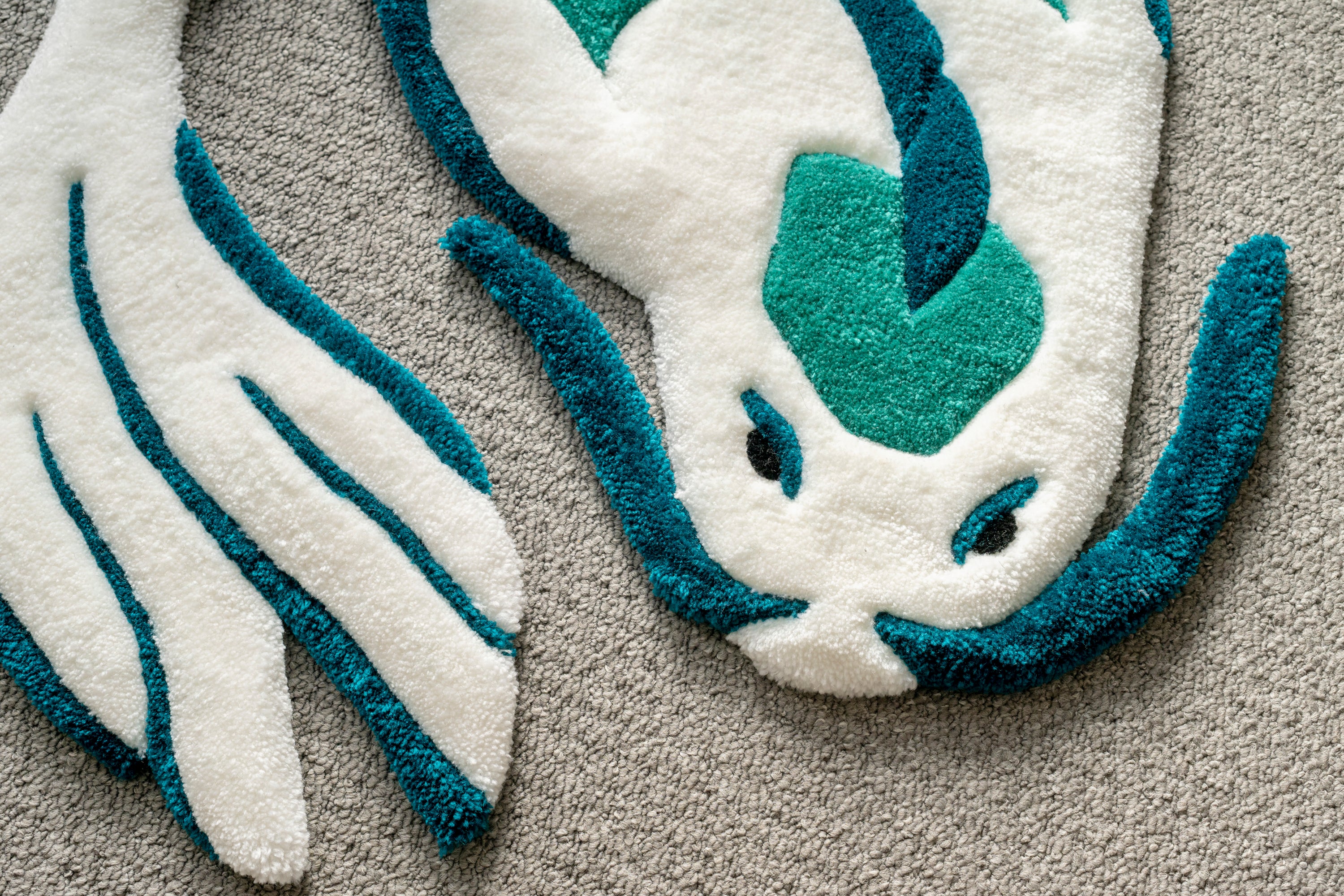 Close-up of a handmade white and teal koi fish rug showing detailed carving, sculpted edges and premium tufted finish.