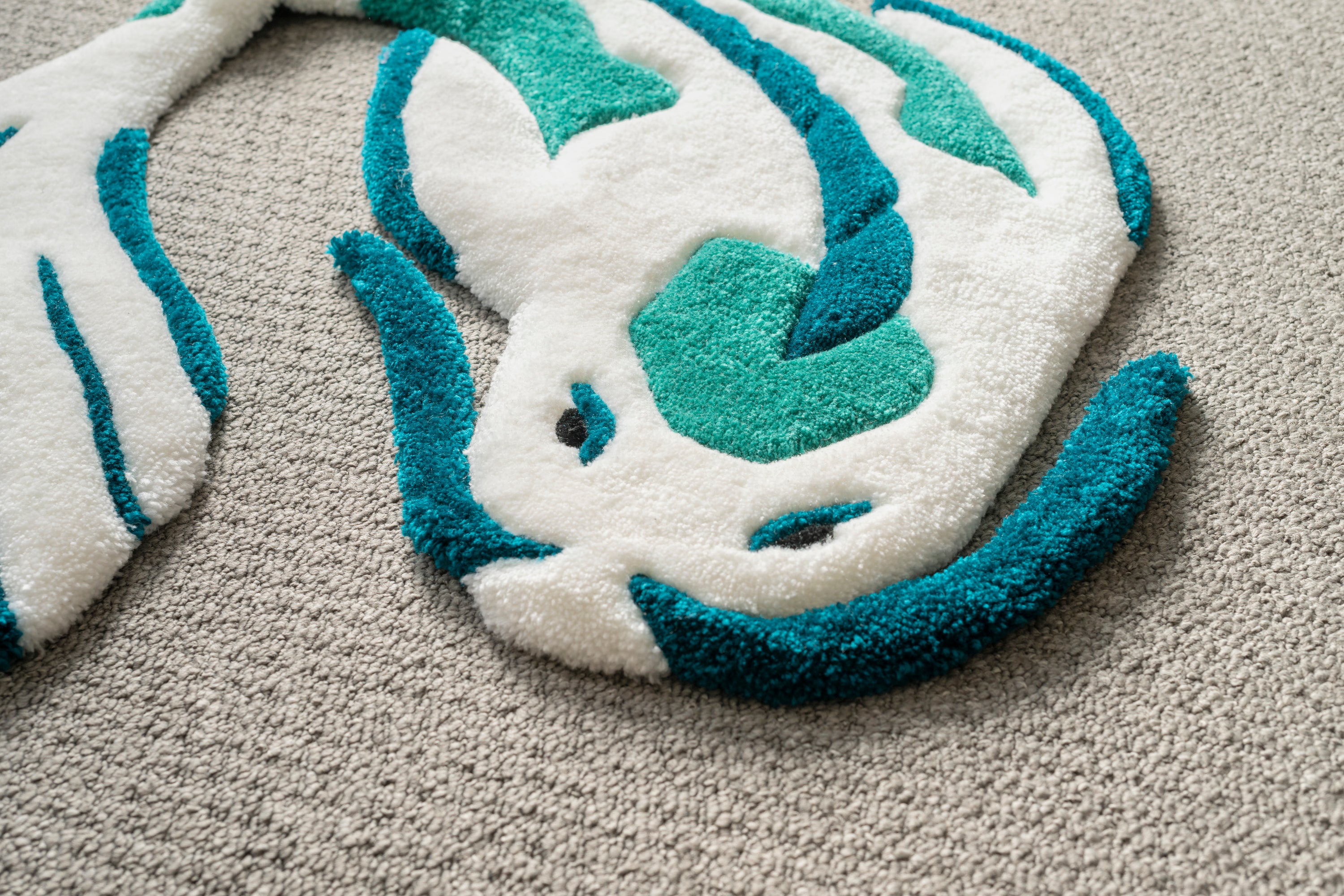 Detailed texture shot of a white and teal koi fish rug crafted from soft acrylic yarn with a smooth low-pile surface.