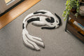 Handmade white and black koi fish rug featuring a flowing Japanese-inspired design with soft low-pile texture and neutral tones.