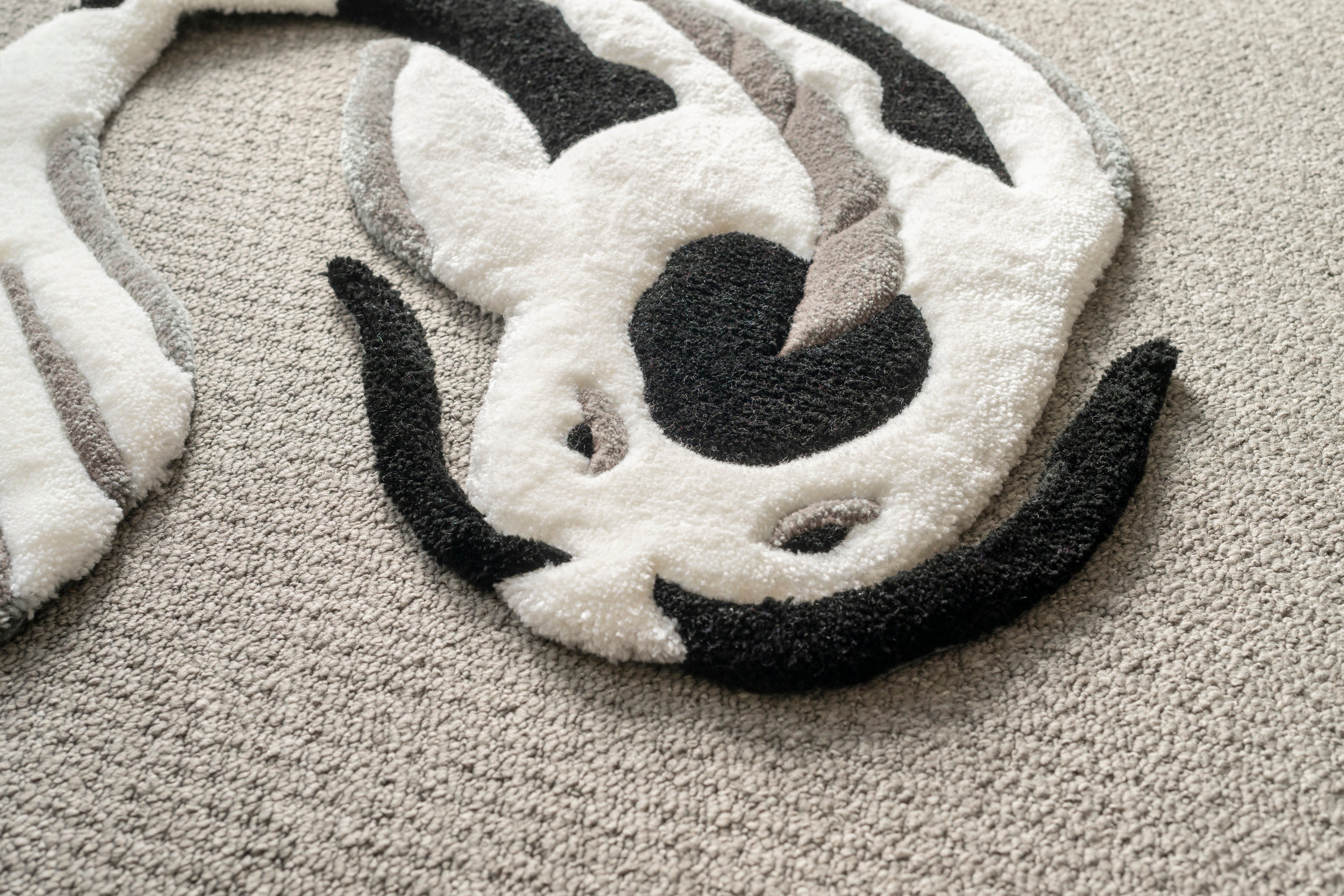 Detailed texture shot of a handmade white and black koi fish rug with a smooth low-pile finish and sculpted design.